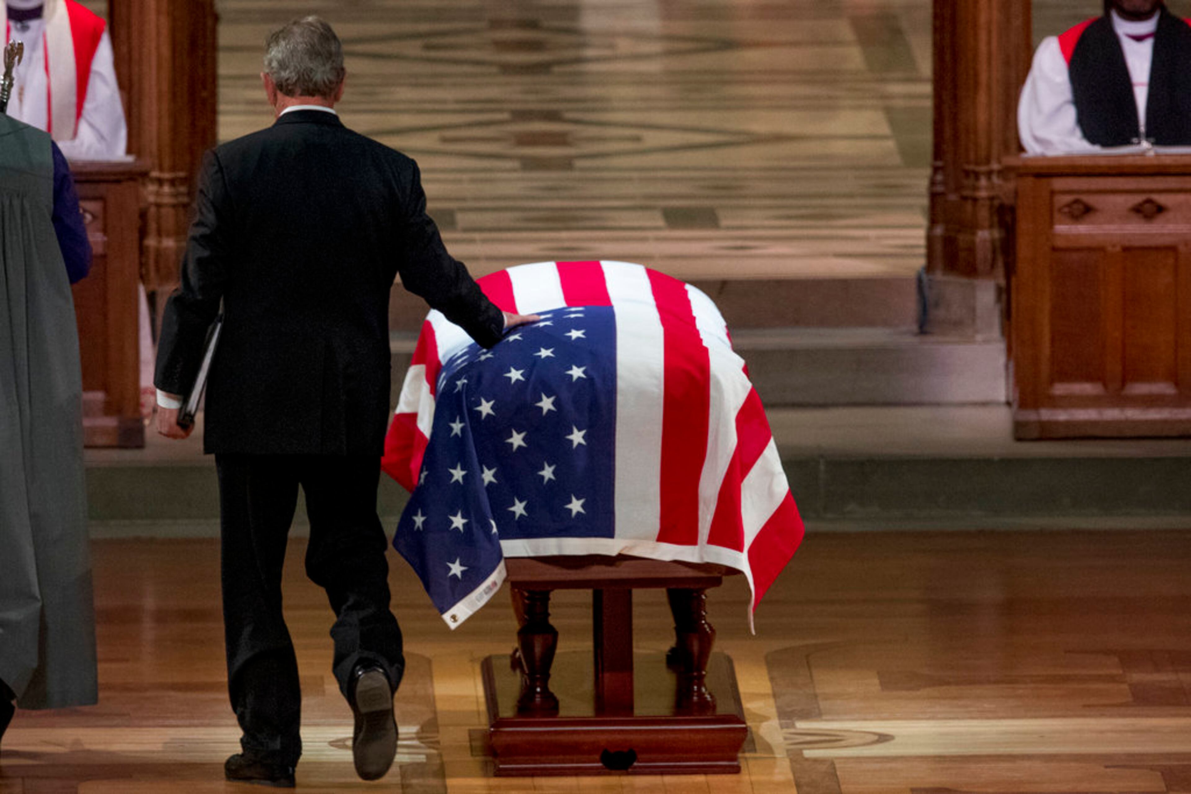 Former President George Bush touches the flag-draped casket of his father, former President George H.W. Bush, as he prepares to speak during his State Funeral at the National Cathedral, Wednesday, Dec. 5, 2018, in Washington. (AP Photo/Andrew Harnik, Pool)