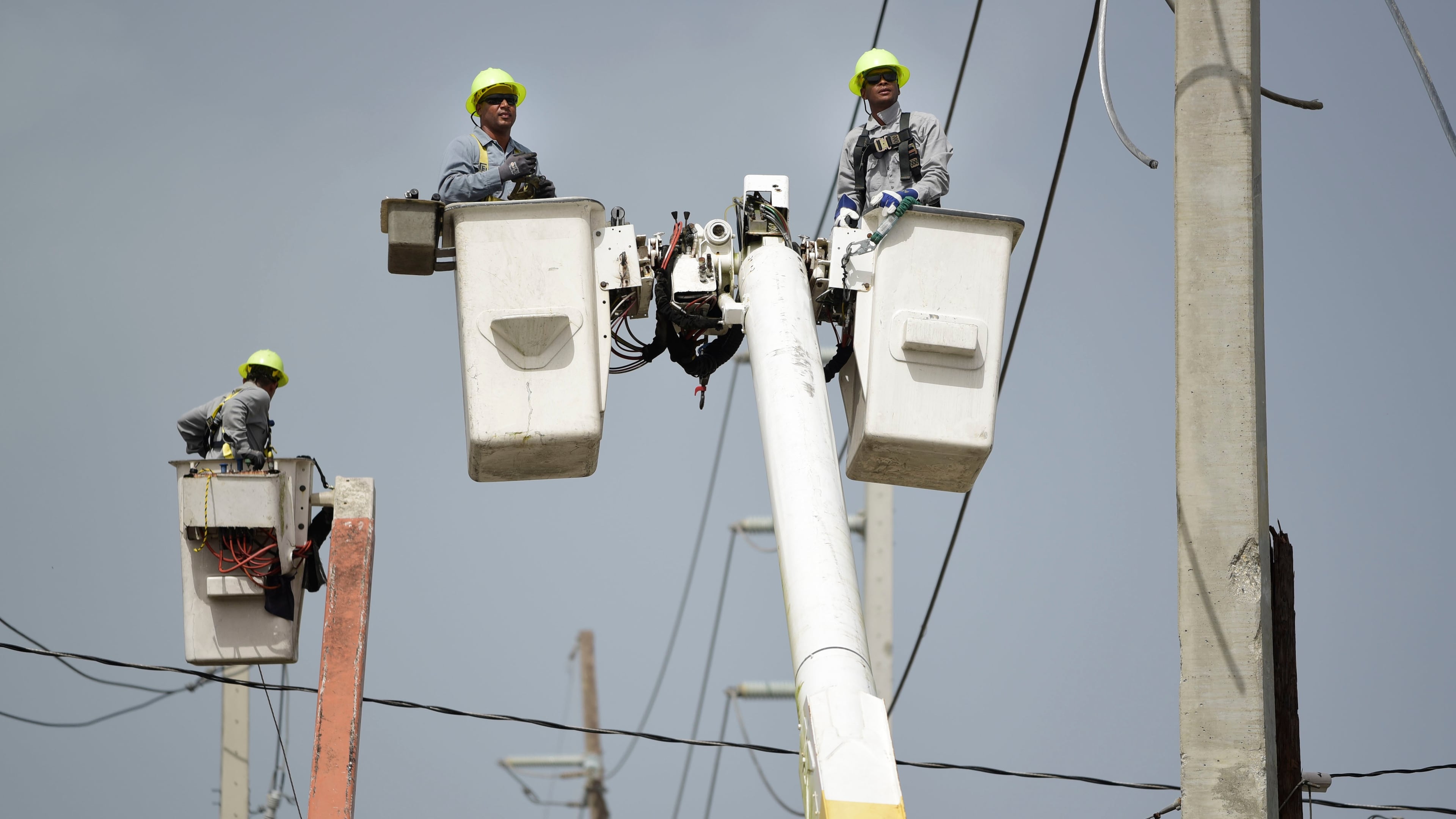 FILE - Puerto Rico Electric Power Authority workers repair distribution lines damaged by Hurricane Maria in the Cantera community of San Juan, Puerto Rico, Oct. 19, 2017. (AP Photo/Carlos Giusti, File)