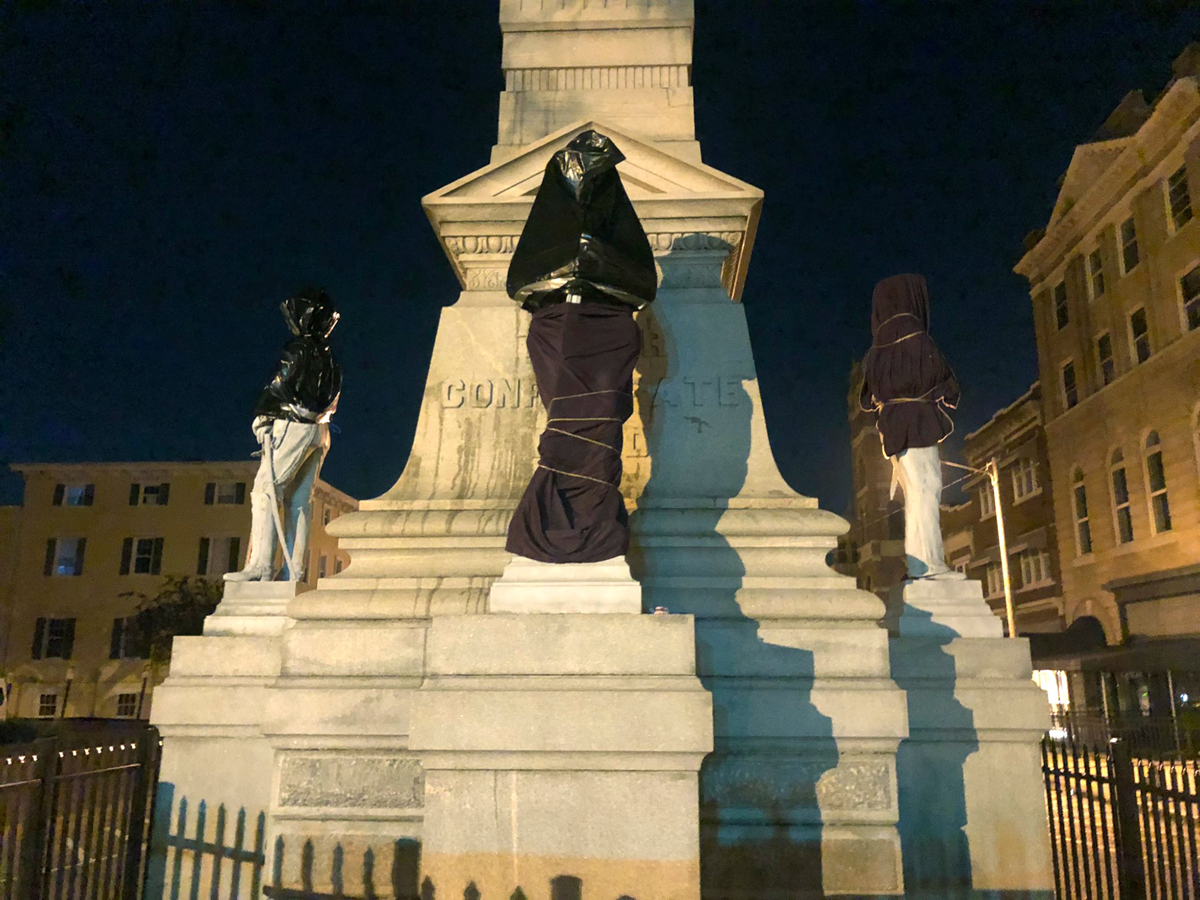 A Confederate monument is covered in sheets and bags early Wednesday in downtown Portsmouth, Virginia.