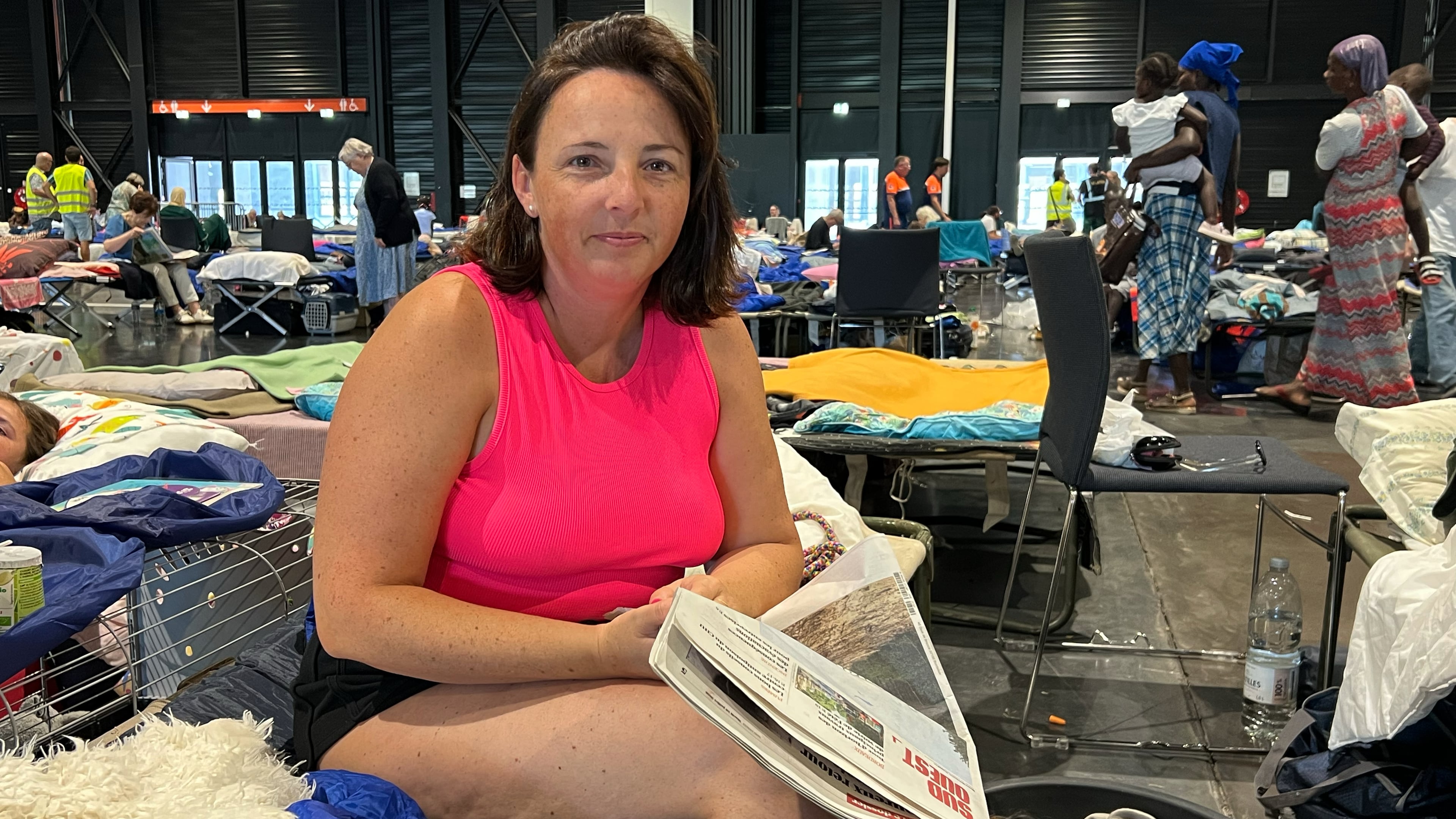 Morgane Bonichot, 40, takes a break from reading a newspaper in an evacuation center in Bordeaux, on Tuesday, July 28, 2026, where she, her daughter, their rabbit and dog are sheltering from wildfires in southwest France. (AP Photo/Eva van Dam)