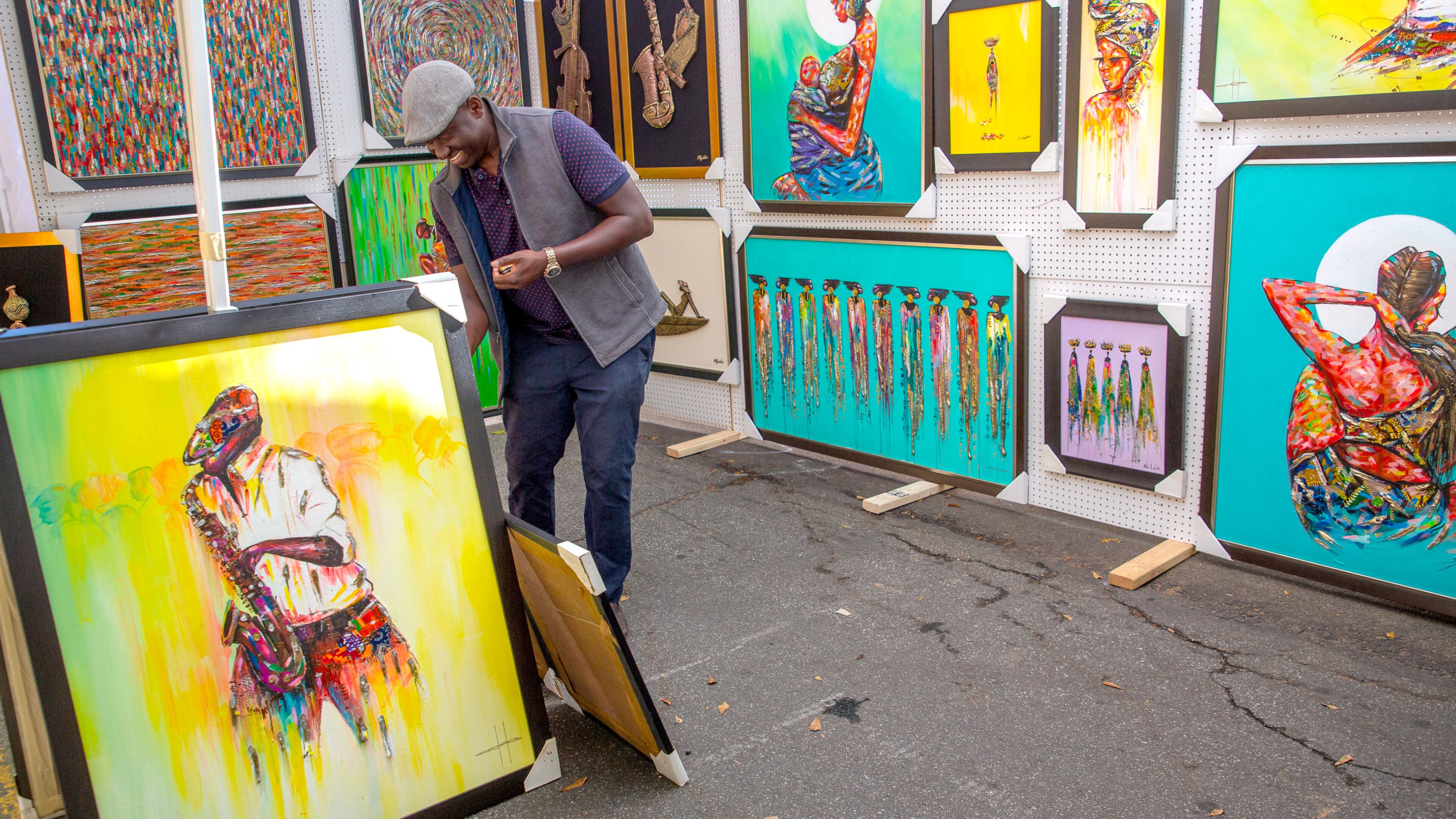 Alfred Addo touches up his painting frames during the Chastain Park Fall Arts Festival Sunday, November 7, 2021. STEVE SCHAEFER FOR THE ATLANTA JOURNAL-CONSTITUTION
