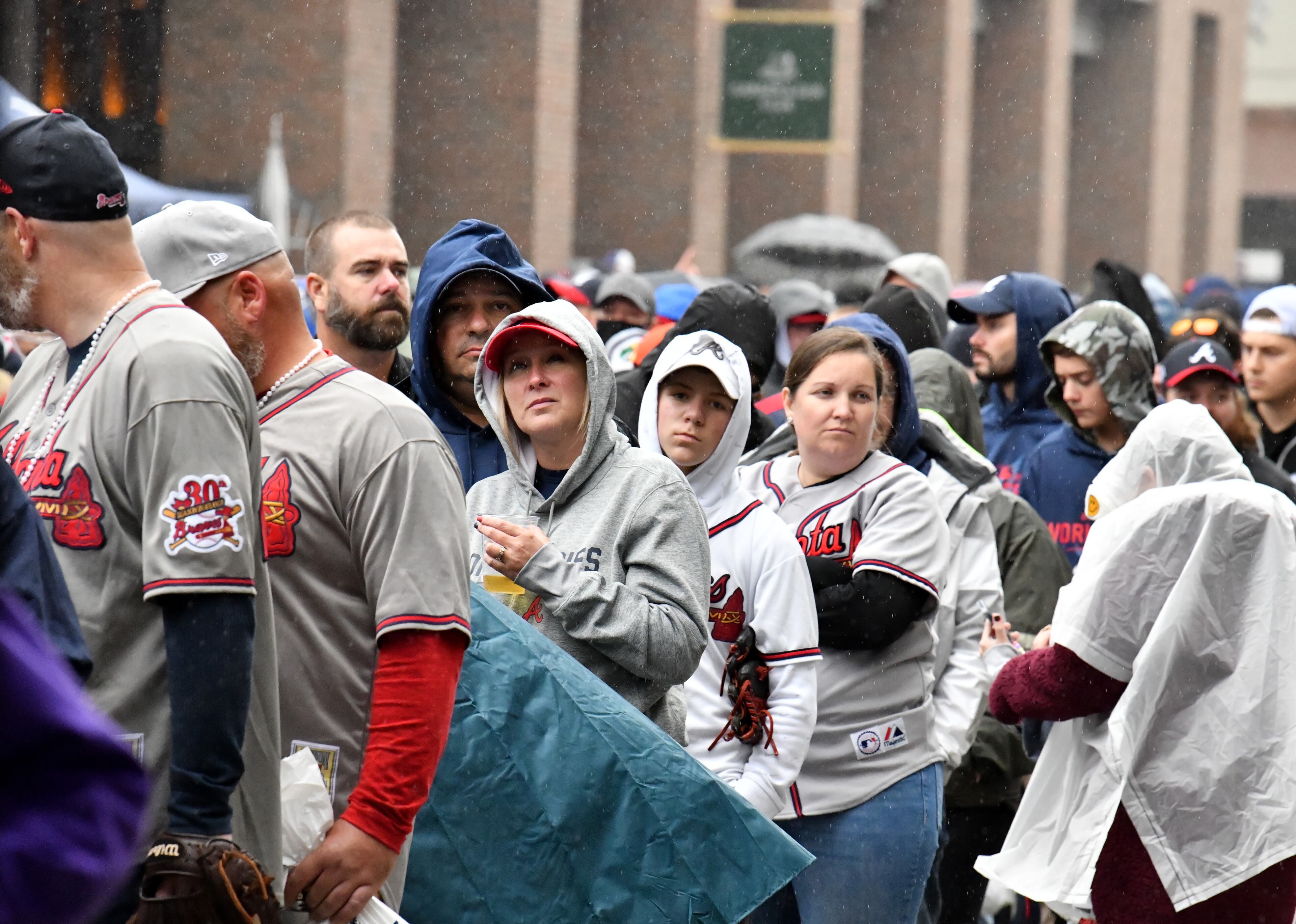 Baseball fans wait in line in the rain prior to Game 4 of baseball's World Series between Atlanta Braves and Houston Astros at Truist Park in Atlanta on Saturday, October 30, 2021. (Hyosub Shin / Hyosub.Shin@ajc.com)