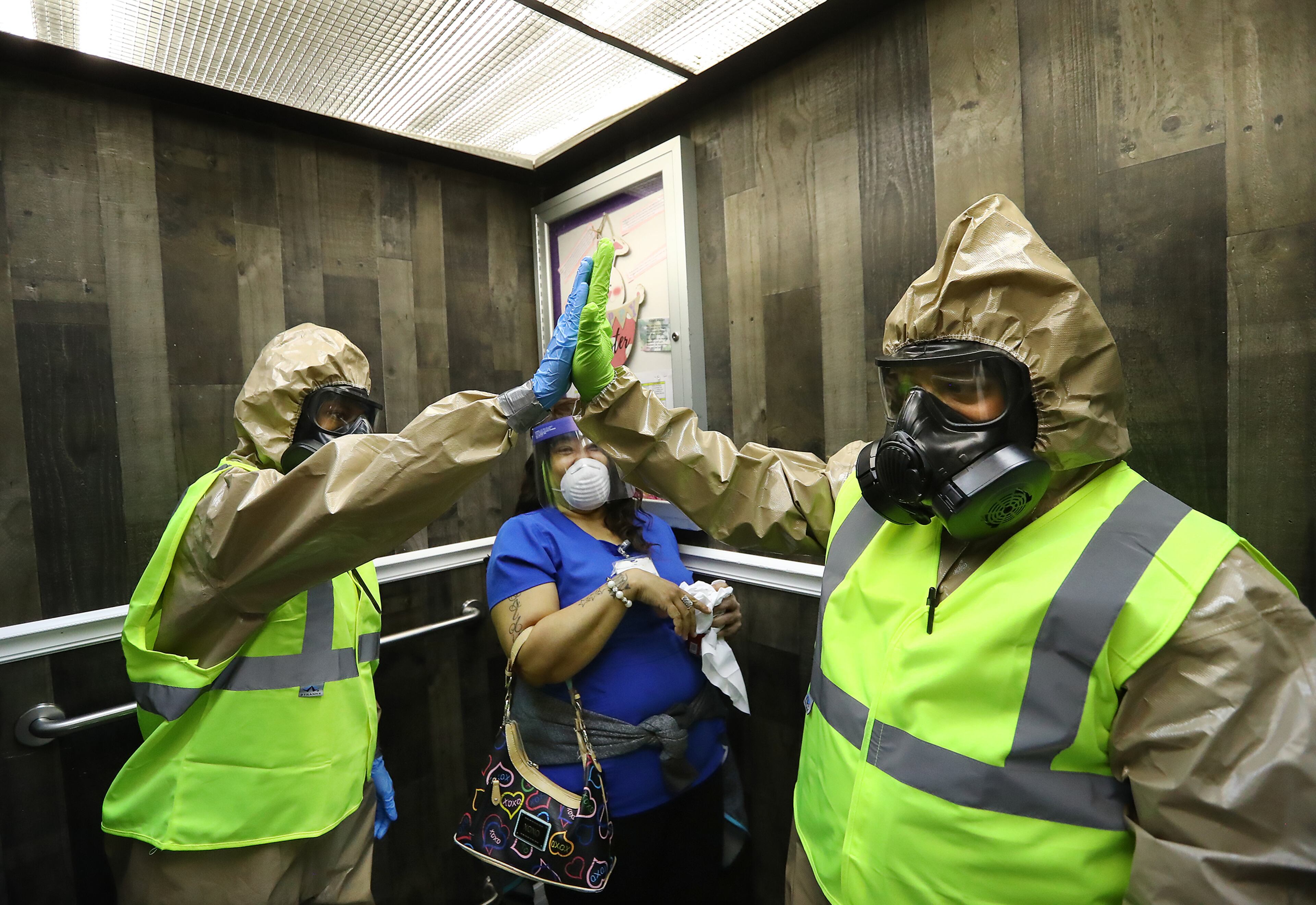 *** DO NOT RUN ONLINE OR PUBLISH UNTIL STORY RUNS *** April 19, 2020 Atlanta: Georgia Army National Guard infection control members Sgt. Daniel Belman (right) and Pfc Cierra Williams (left) with the 265th Chemical Battalion are able to give each other a high five in full protective gear on the elevator ride down after their unit finished disinfecting and helping doctors collect swabs from residents to test for COVID-19 at Legacy Transitional Care on Sunday, April 19, 2020, in Atlanta. Curtis Compton
