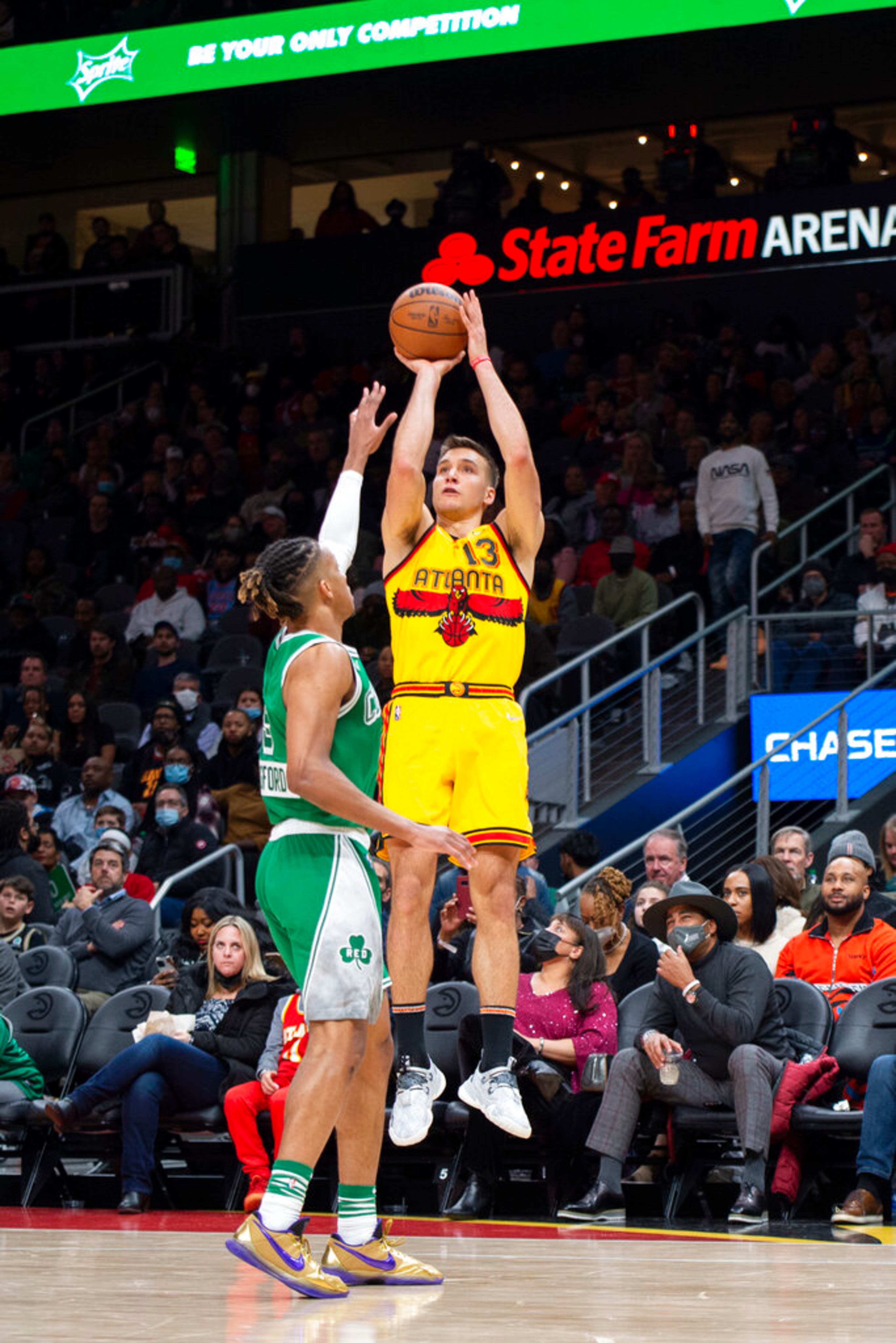 Atlanta Hawks guard Bogdan Bogdanovic (13) shoots over Boston Celtics guard Romeo Langford (9) during the second half of an NBA basketball game Friday, Jan. 28, 2022, in Atlanta. (AP Photo/Hakim Wright Sr.)
