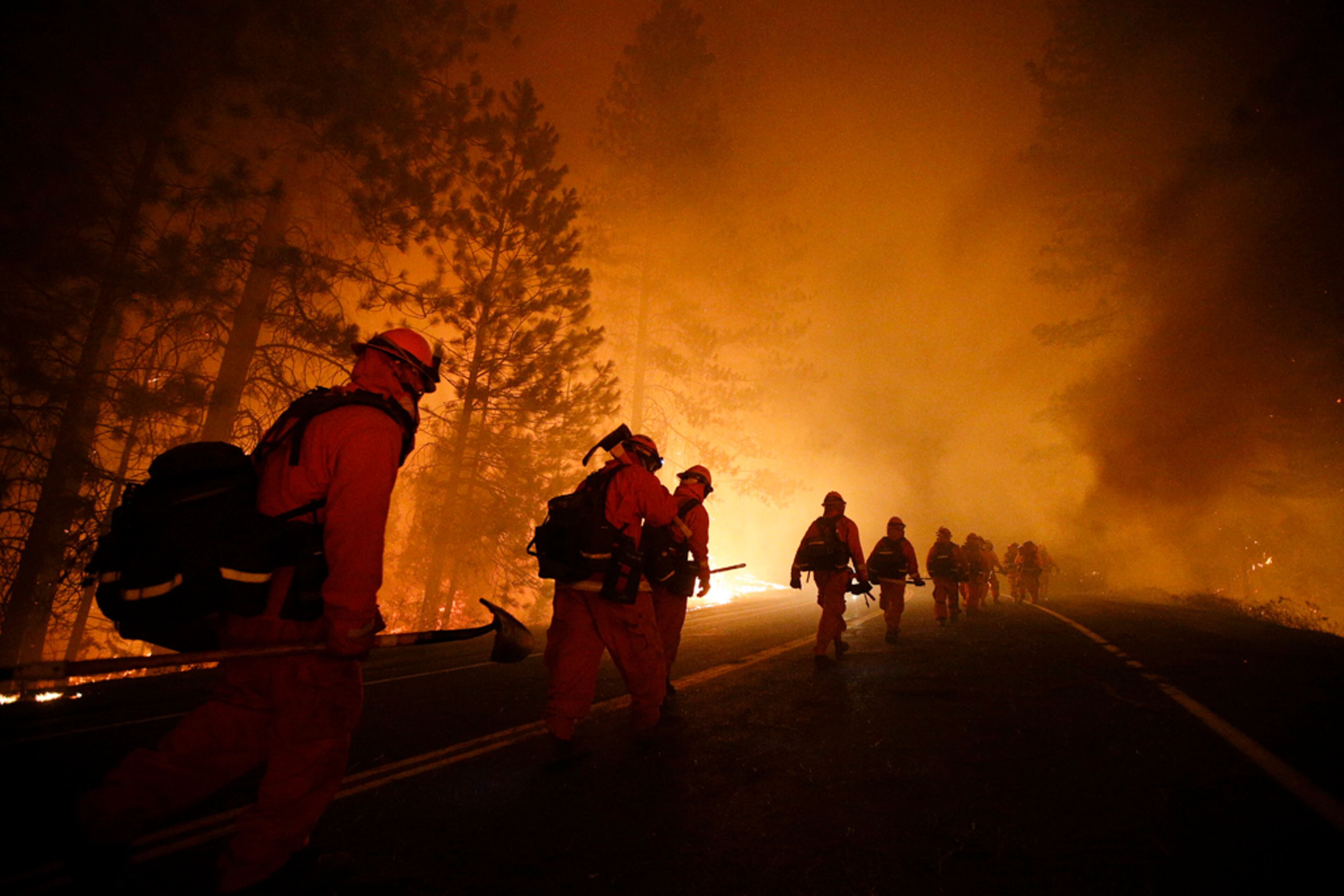 Inmate firefighters walk along Highway 120 after a burnout operation as firefighters continue to battle the Rim Fire near Yosemite National Park, Calif., on Sunday, Aug. 25, 2013. Fire crews are clearing brush and setting sprinklers to protect two groves of giant sequoias as a massive week-old wildfire rages along the remote northwest edge of Yosemite National Park. (AP Photo/Jae C. Hong)