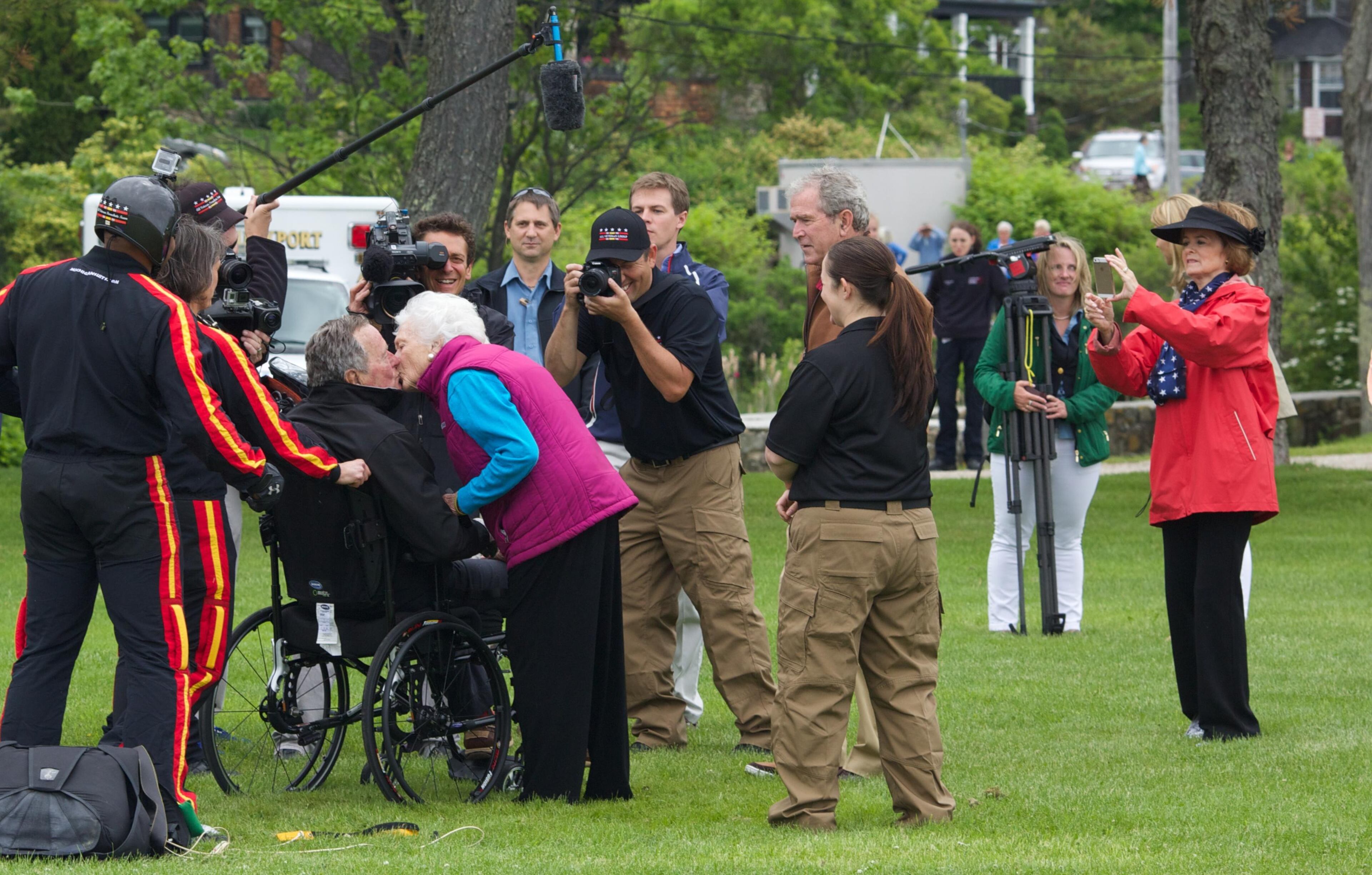 FILE PHOTO: Former first lady Barbara Bush greets her husband and former U.S. President George H.W. Bush with a kiss after his successful skydive down to St. Anne's Episcopal Church on June 12, 2014 in Kennebunkport, Maine. The President is celebrating his 90th birthday today. (Photo by Eric Shea/Getty Images)