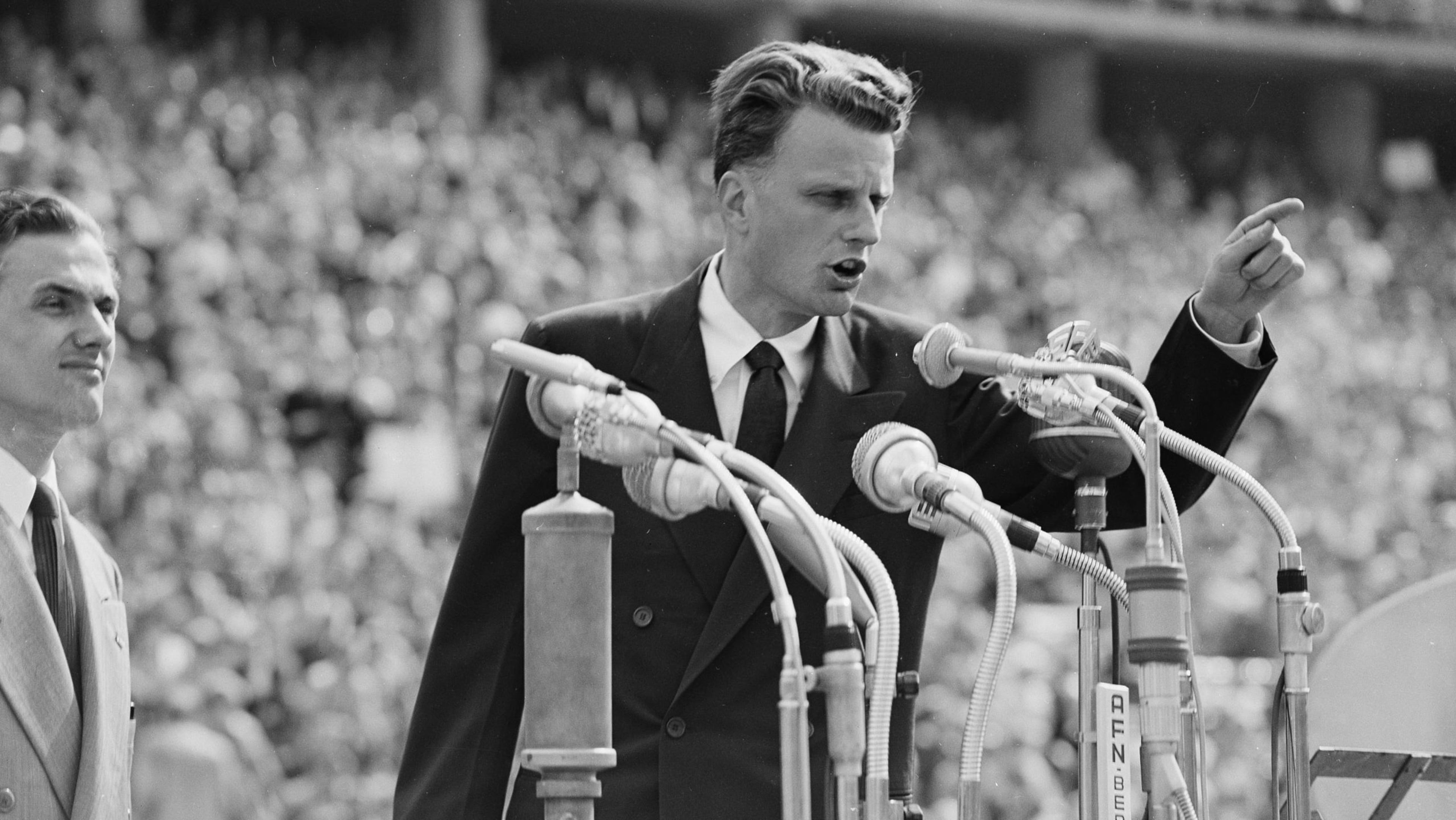 FILE - In this June 27, 1954 file photo, Evangelist Billy Graham speaks to over 100,000 Berliners at the Olympic Stadium in Berlin, Germany. Graham, who transformed American religious life through his preaching and activism, becoming a counselor to presidents and the most widely heard Christian evangelist in history, has died. Spokesman Mark DeMoss says Graham, who long suffered from cancer, pneumonia and other ailments, died at his home in North Carolina on Wednesday, Feb. 21, 2018. He was 99. (AP Photo, File)