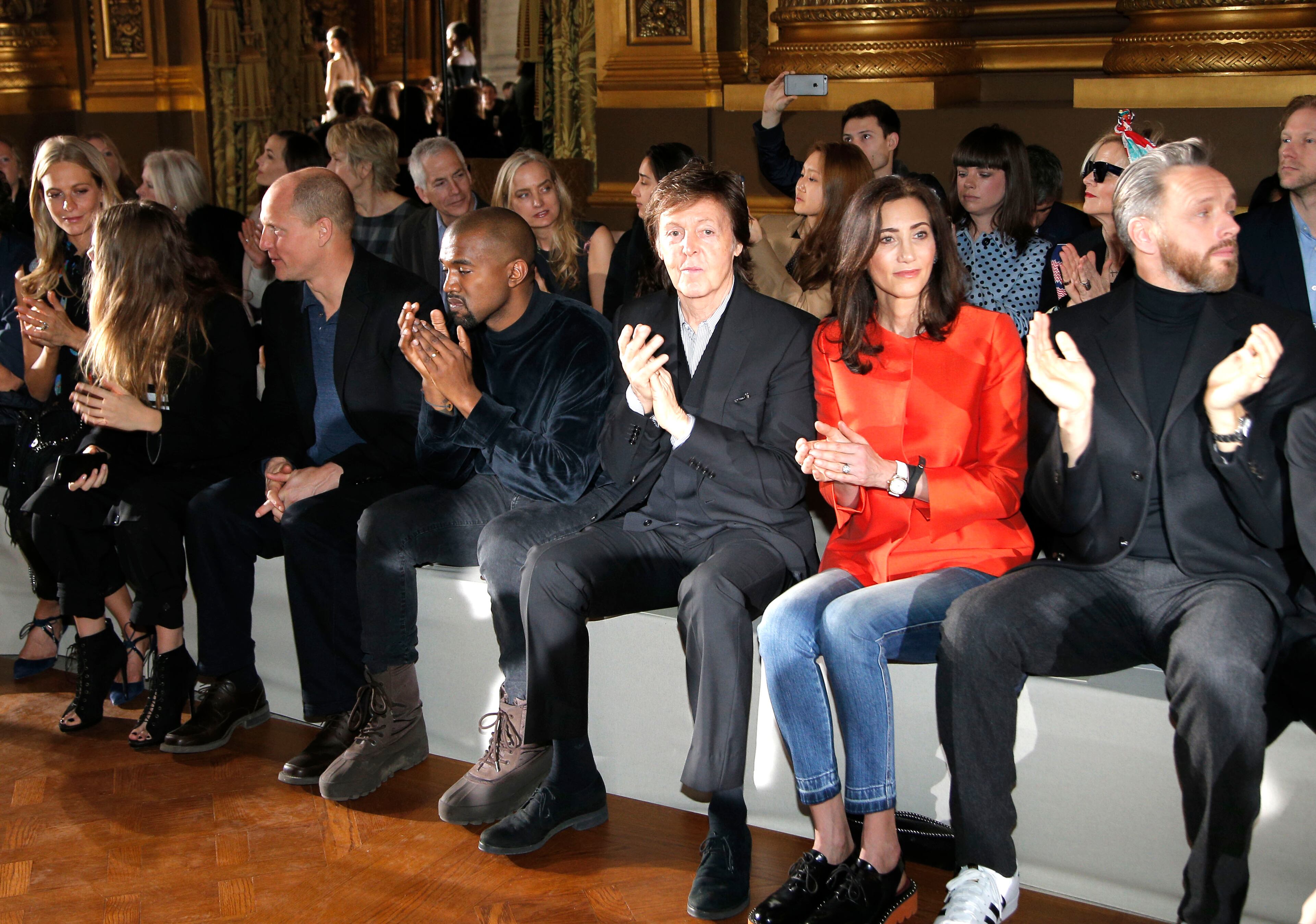 From left, Poppy Delevingne, Cara Delevingne, Woody Harrelson, Kanye West, Paul McCartney, his wife Nancy Shevell and husband of Stella, Alasdhair Willis front row at Stella McCartney's ready to wear fall-winter 2015-2016 fashion collection during Paris Fashion Week, Paris, France, Monday, March 9, 2015. (AP Photo/Thibault Camus)