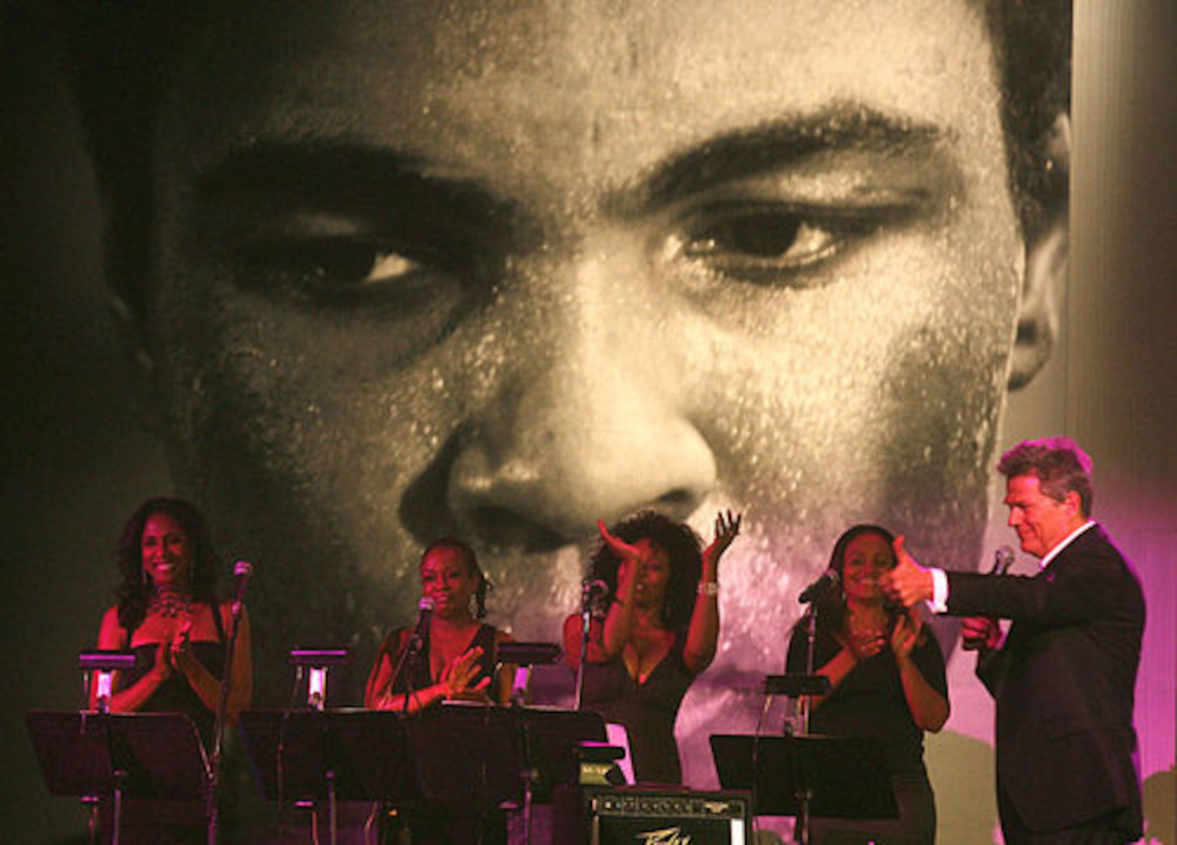 A portrait of Muhammad Ali looks down on the stage as David Foster conducts the charity auction at Muhammad Ali's Celebrity Fight Night.