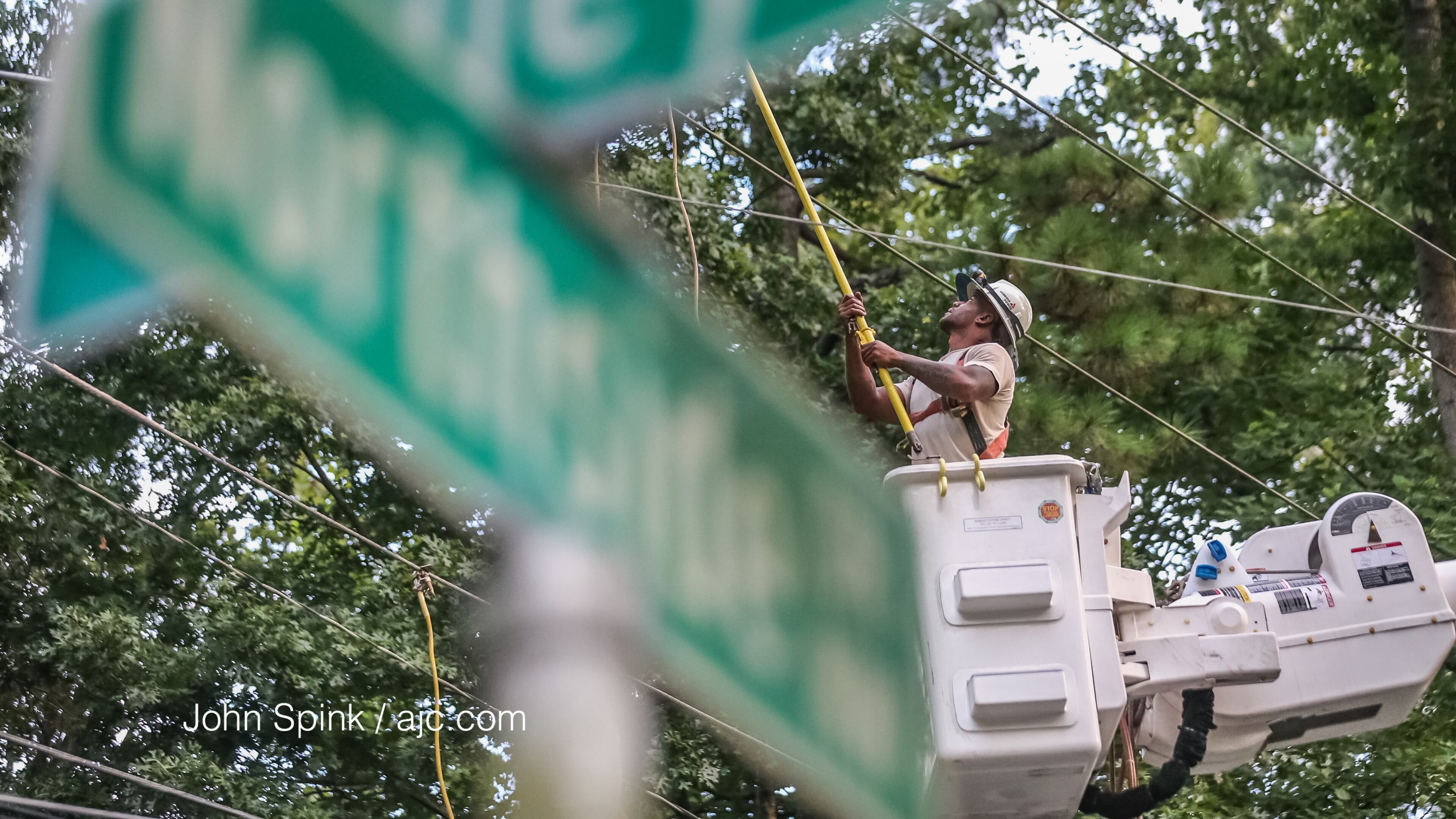 James Williams with Georgia Power worked to restore service Friday on Northside Drive after storms sent a tree and power lines down. JOHN SPINK / JSPINK@AJC.COM