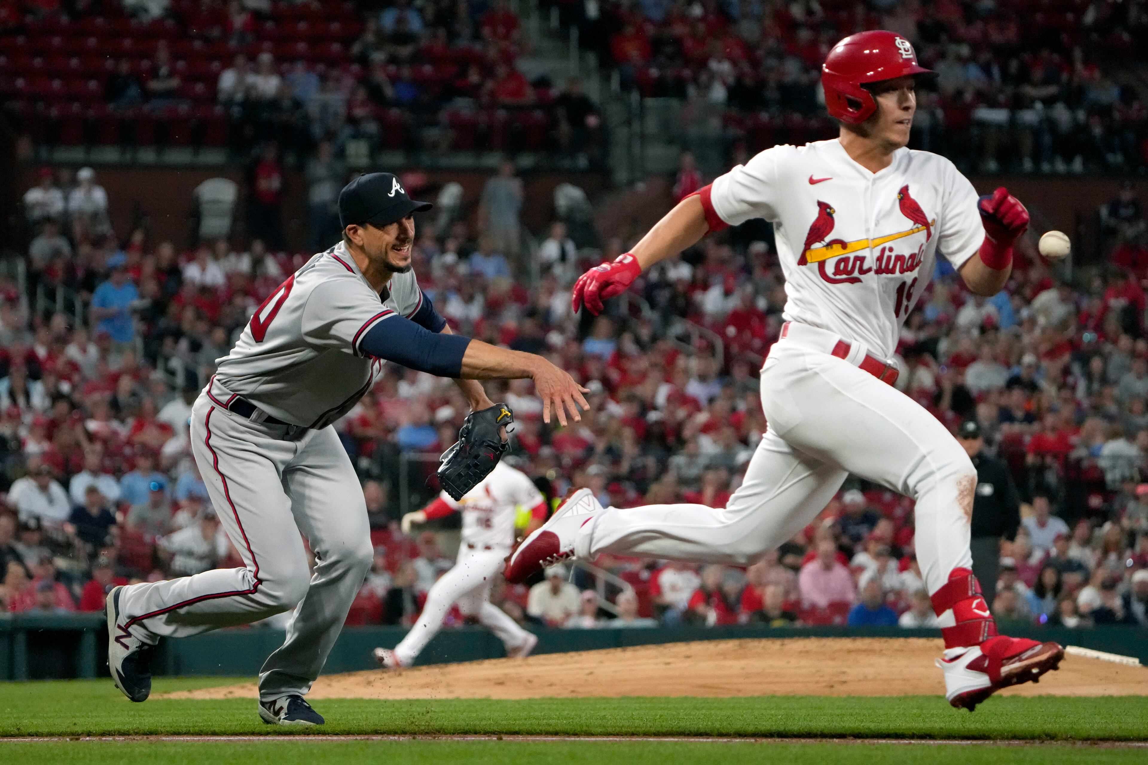 Braves pitcher Charlie Morton (left) tosses to first for the out against Cardinals baserunner Tommy Edman (right) during the second inning of a baseball game Monday, April 3, 2023, in St. Louis.