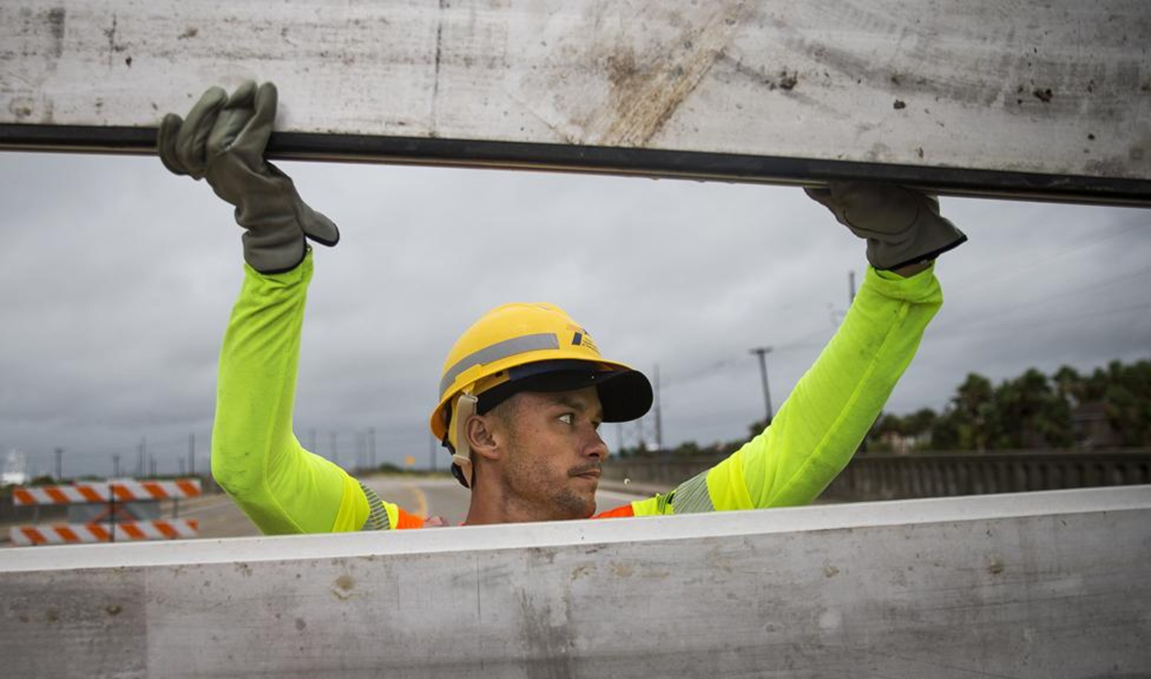 TxDOT worker Hunter Weinrich guides an aluminum slat into place while installing the final portion of a surge wall on TX-361 leading to the Port Aransas ferry in Aransas Pass, Texas, on Friday, August 25, 2017. Hurricane Harvey is expected to make landfall on the Texas coast tonight or early Saturday morning as a category 3 hurricane.