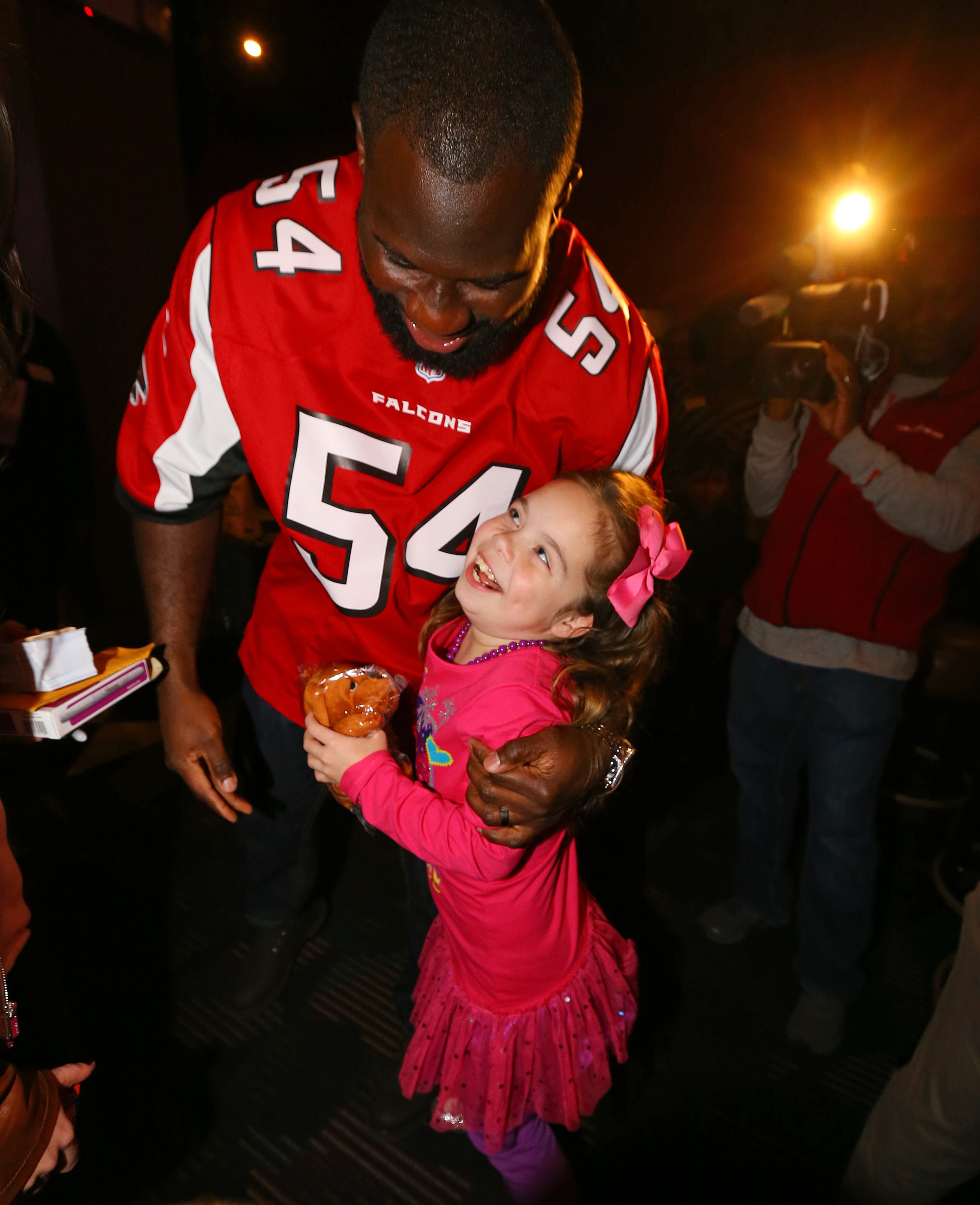 Nine-year old Belle Helton gets a hug from Atlanta Falcons linebacker Stephen Nicholas.