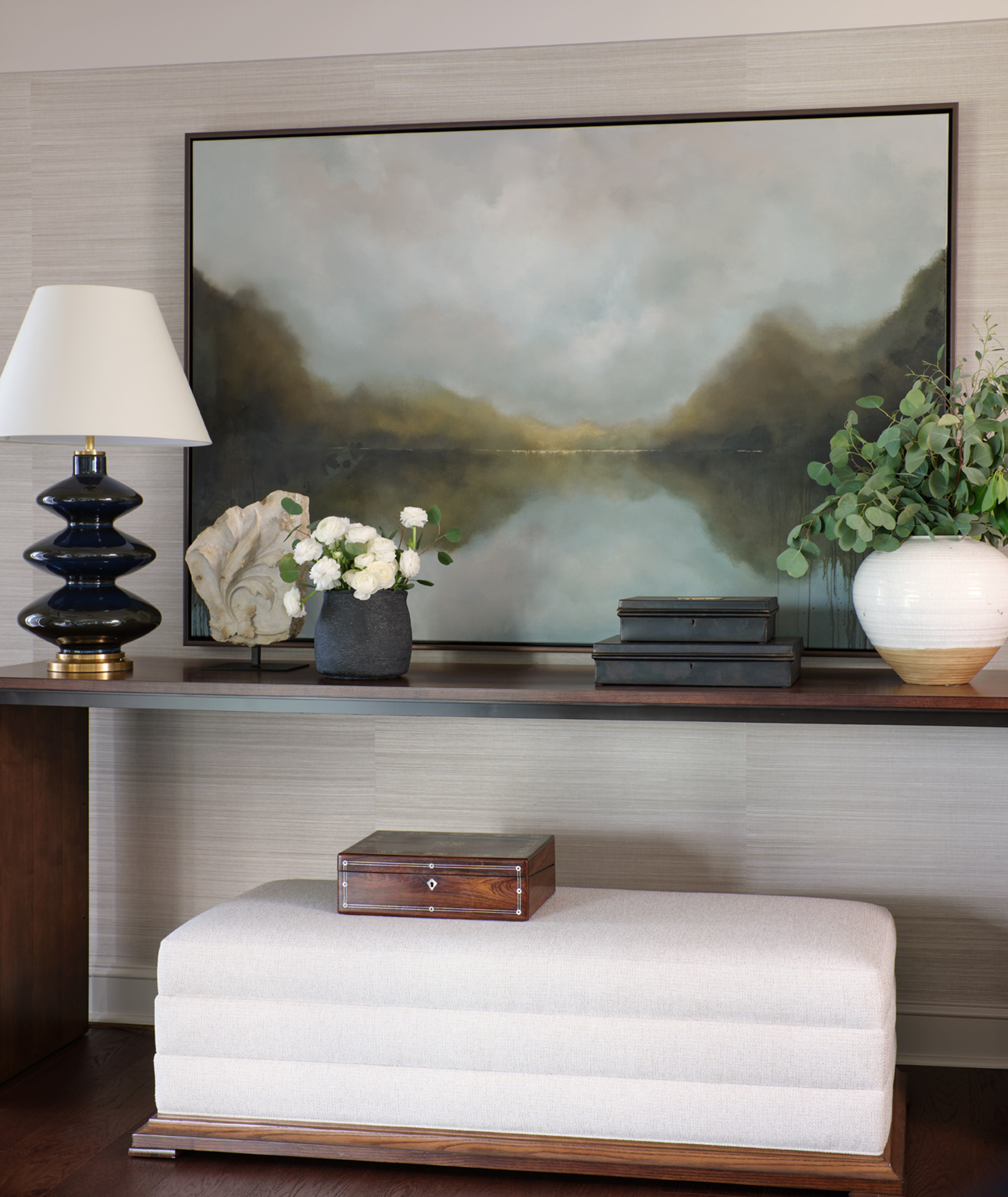 A home should be filled with meaningful objects that reflect unity, warmth and personality. Original artwork can be one of the most profound ways to elevate a space into something quite special. This commissioned large piece of art has meaning to the homeowners while also serving as a dramatic focal point over the understated but large in scale console table. The space is finished with a custom ottoman underneath to add textile warmth and extra seating while entertaining. Text by Ashley Miller. Courtesy of Mali Azima