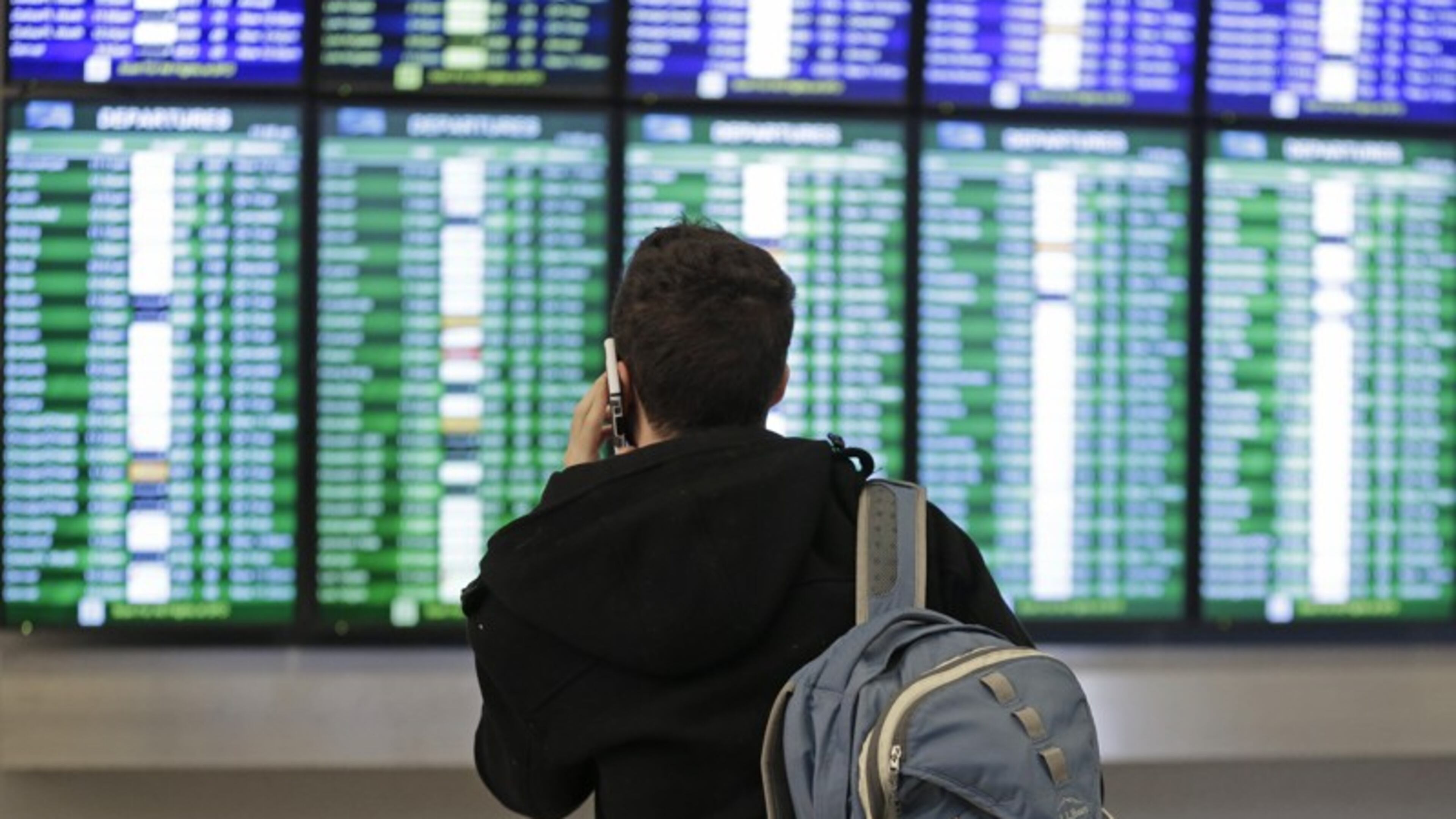 FILE - In this Friday, Jan. 22, 2016, file photo, a traveler speaks on the phone as he views the arrival and departure board at San Francisco International Airport in San Francisco. U.S. airlines have canceled several thousand flights through Tuesday, March 14, 2017, as a winter storm heads toward the Northeast. The major airlines are waiving ticket-change fees that range up to $200 for customers who want to change their travel plans. Restrictions vary by airline. (AP Photo/Ben Margot, File)