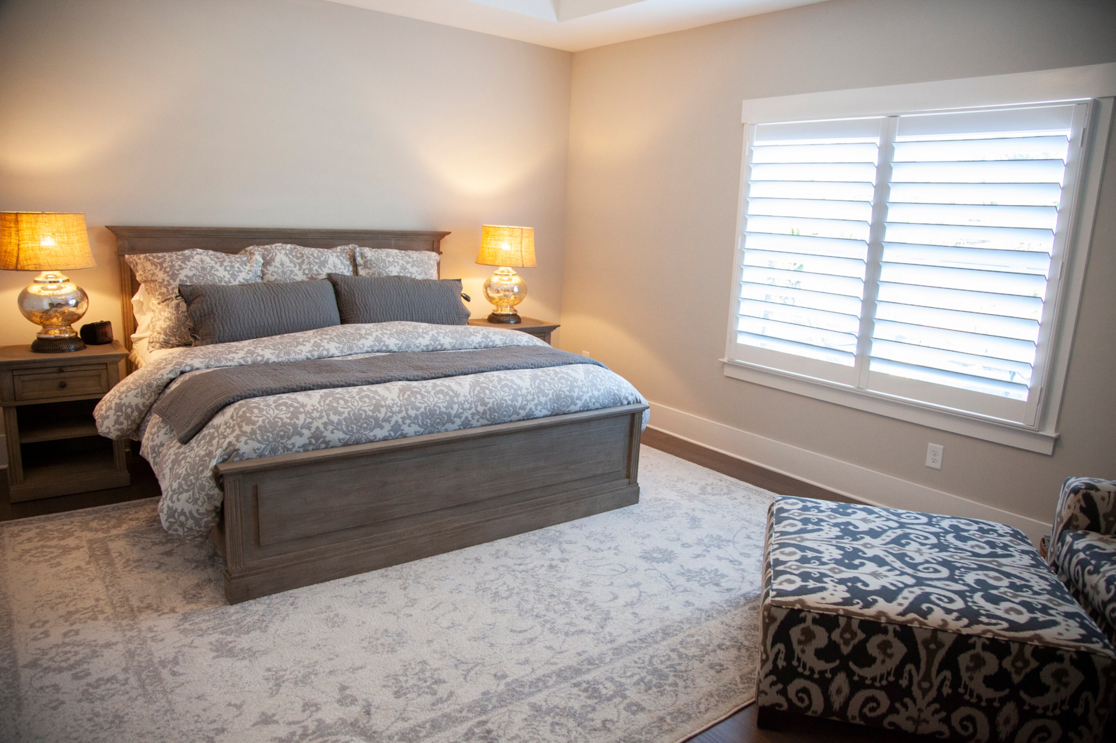 The transitional interiors include the use of grays and off-whites. In the master, the bed and side tables are from Pottery Barn.