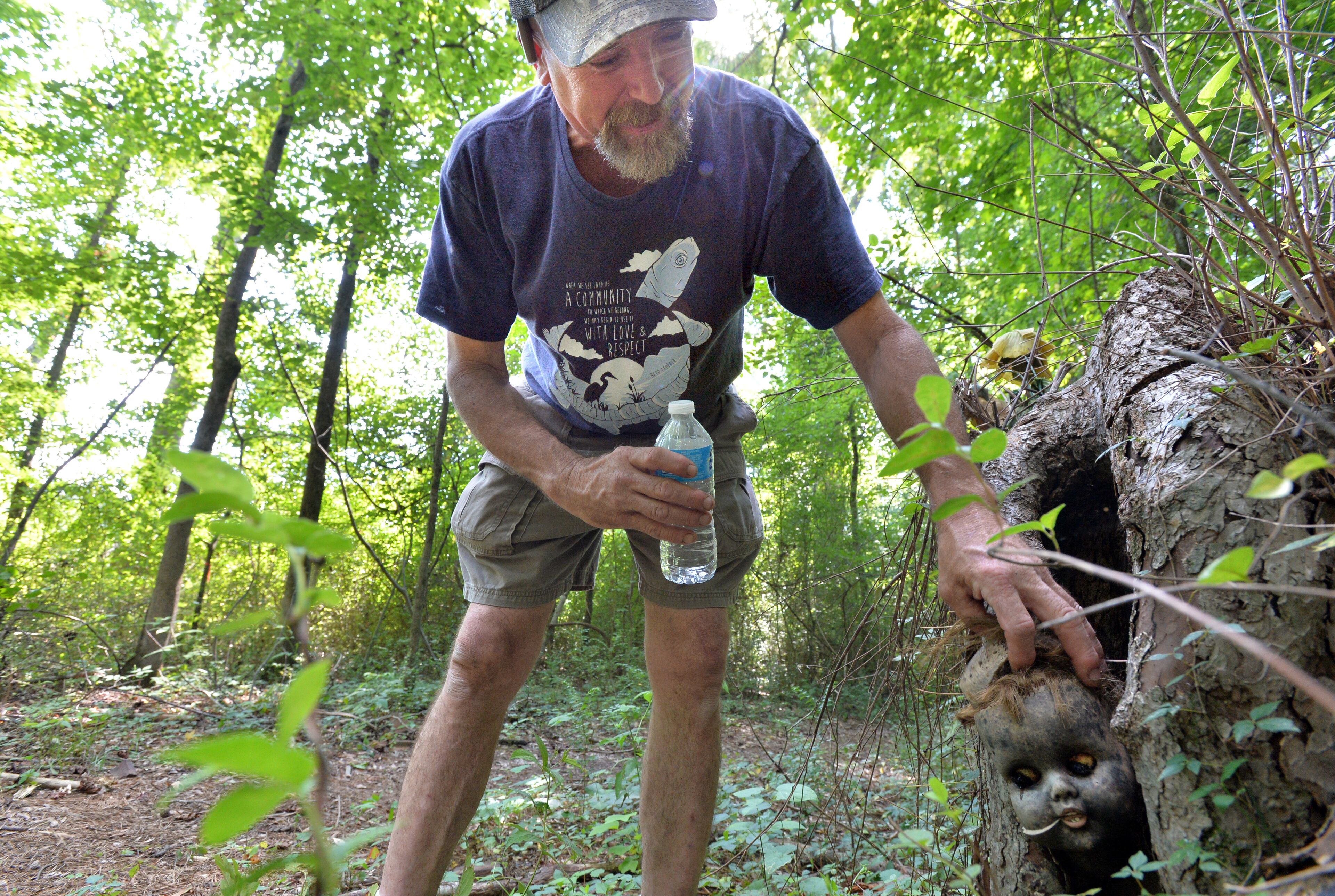 Joel Slaton, who first started Doll's-Head Trail, maintains one of "found art" pieces at on the trail at Constitution Lakes Park near the intersection of South River Industrial Boulevard Road and Moreland Avenue on Friday, July 29, 2014. It's called Doll's-Head Trail because of many of the pieces are created with trash, much of it doll heads, that gets deposited when the South River floods.