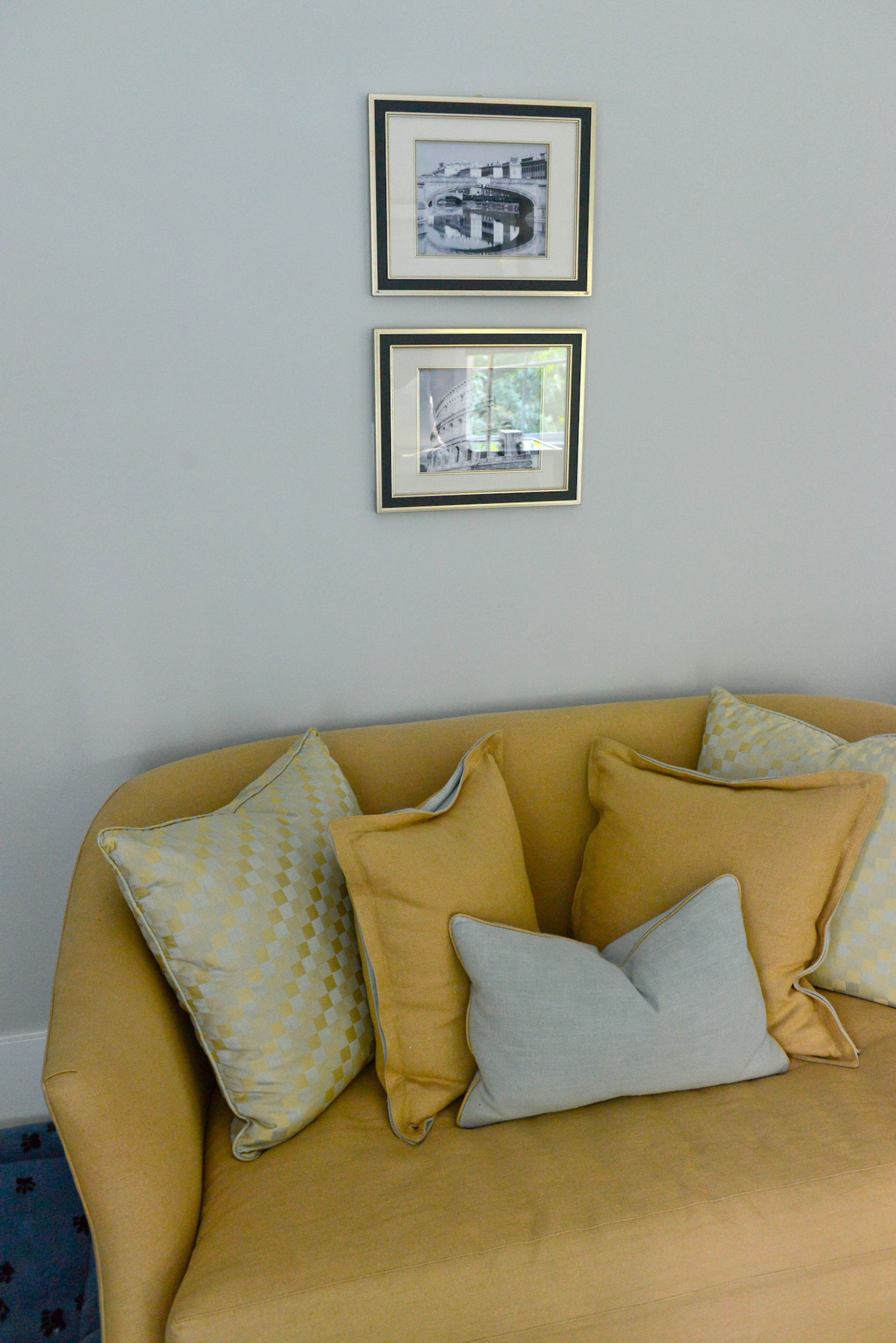 Cushions and a bright sofa pop against the light gray walls in homeowner Nadine Bratti's master bedroom.