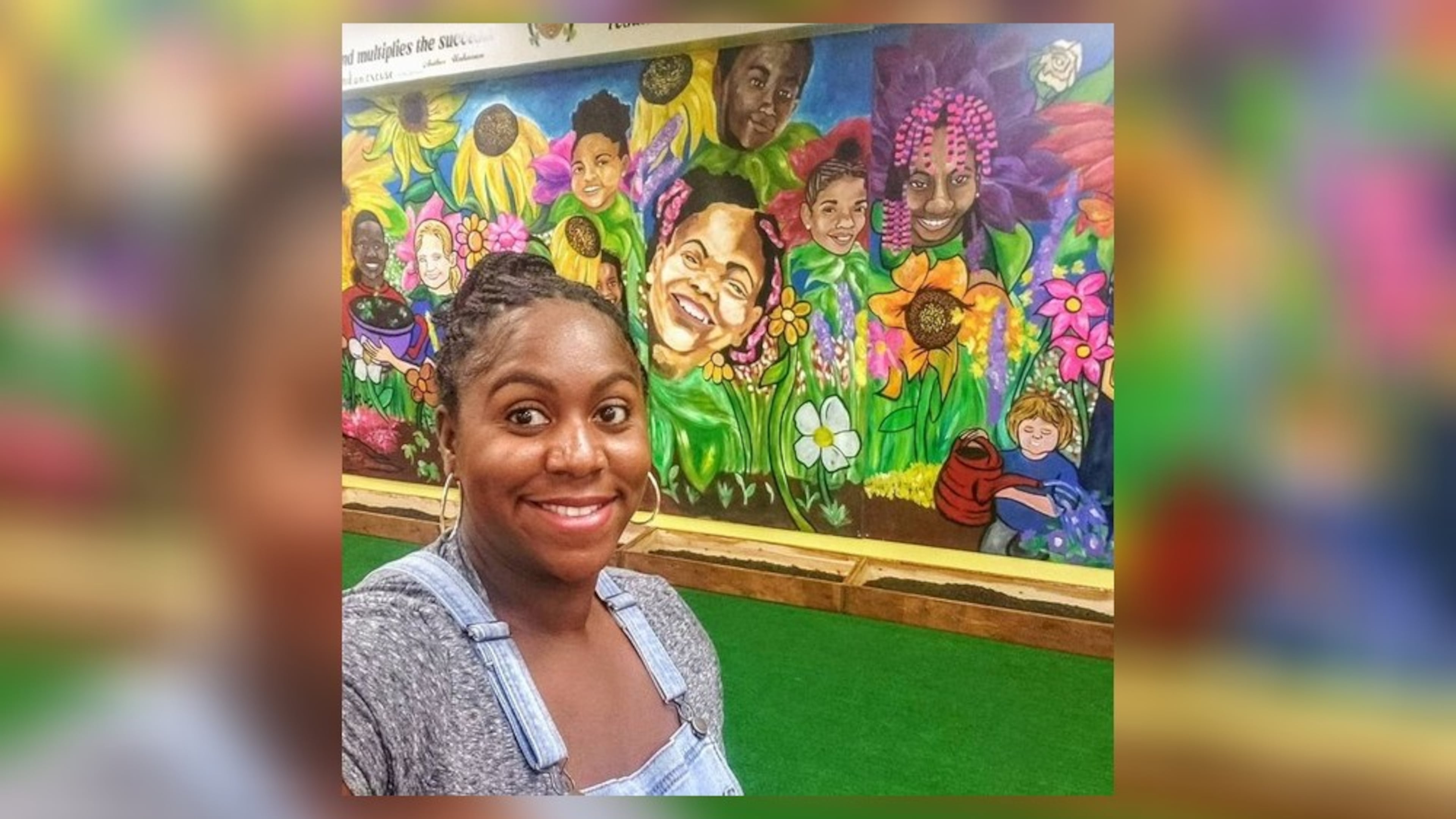 Ashley D. stands in front of her “Grow” mural painted on a wall at the Barack & Michelle Obama Academy in Atlanta.