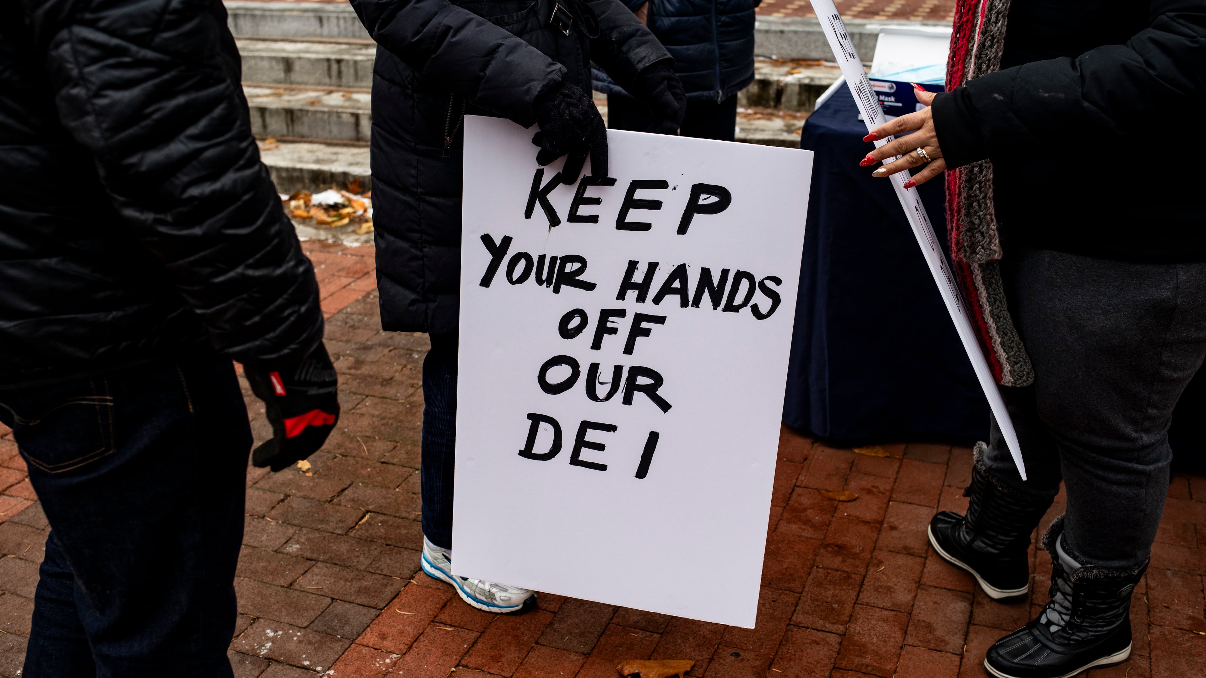 A sign is held up during a rally to protect funding for Diversity, Equity and Inclusion at the University of Michigan in Ann Arbor, Mich., Dec. 2, 2024. As the Trump administration threatens to strip accrediting bodies of their power, many are scrambling to purge diversity requirements. (Emily Elconin/The New York Times)