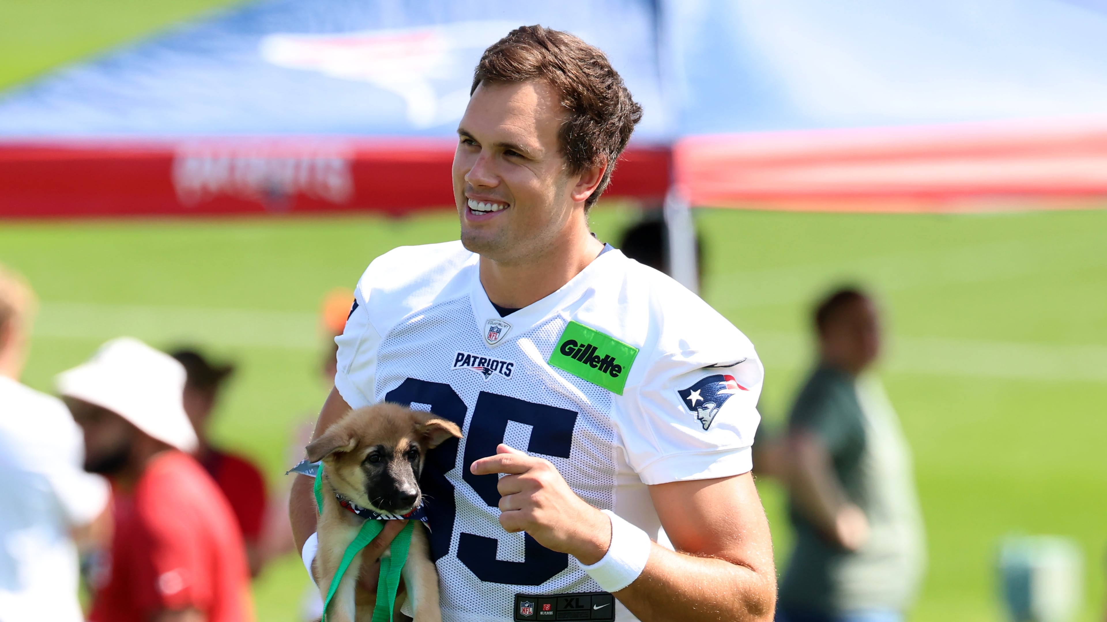 New England Patriots tight end Hunter Henry walks with a dog, part of the team's adopt a dog program at the team's first day of NFL football training camp, Saturday, July 25, 2026, in Foxborough, Mass. (AP Photo/Mark Stockwell)