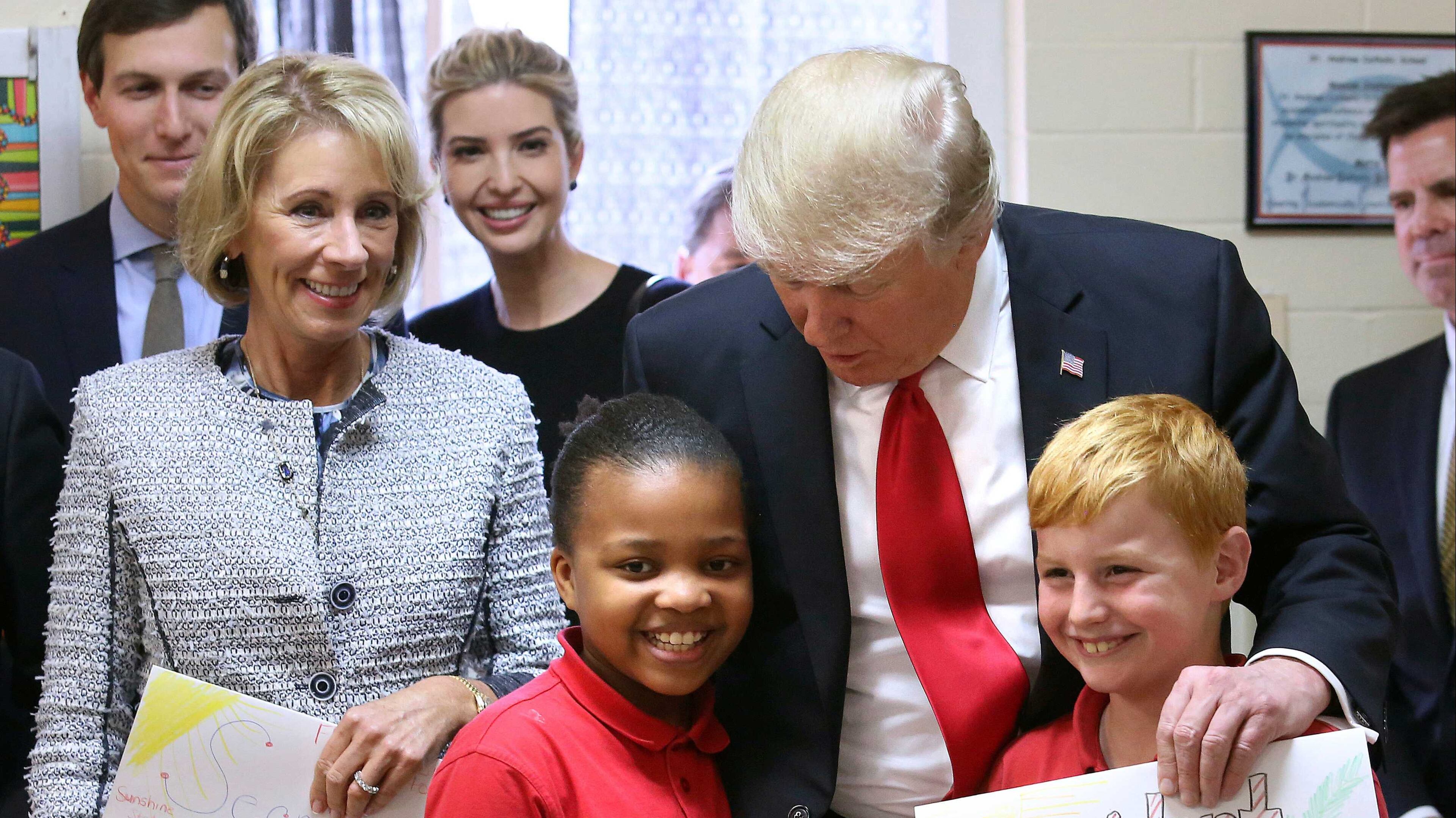 President Donald Trump thanks fourth-graders Janayah Chatelier and Landon Fritz for the homemade greeting cards they presented during his visit to St. Andrew Catholic School in Orlando, Fla., Friday, March 3, 2017. With the president, from left to right, are: Trump son-in-law Jared Kushner; U.S. Secretary of Education Betsy DeVos, and Trump daughter Ivanka Trump. (Joe Burbank/Orlando Sentinel via AP)