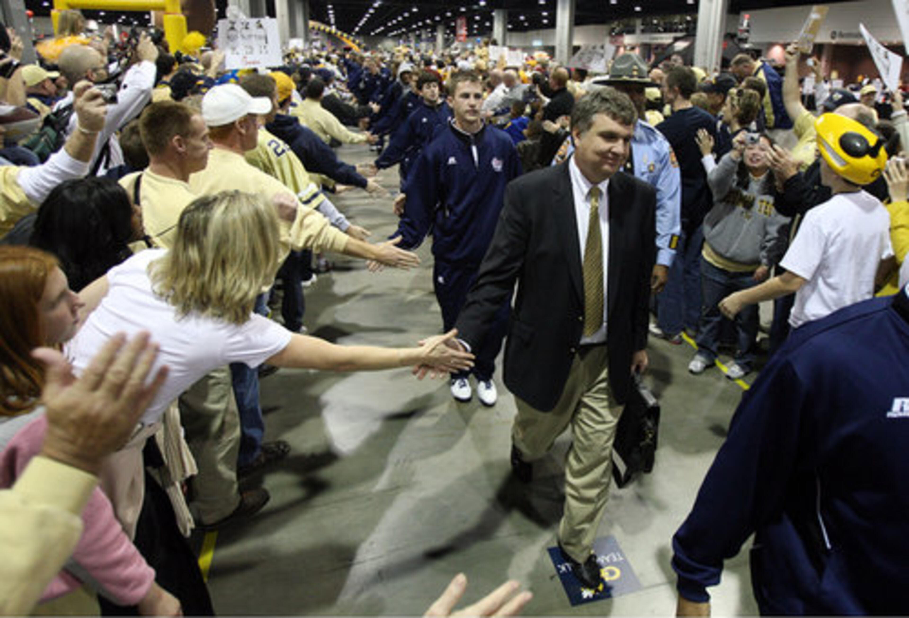 Georgia Tech head coach Paul Johnson leads the team through a sea of fans at the Coca-Cola Chick-fil-A Bowl Fan Fest at the Georgia World Congress Center as they arrive to face the LSU Tigers at the Chick-fil-A Bowl at the Georgia Dome.