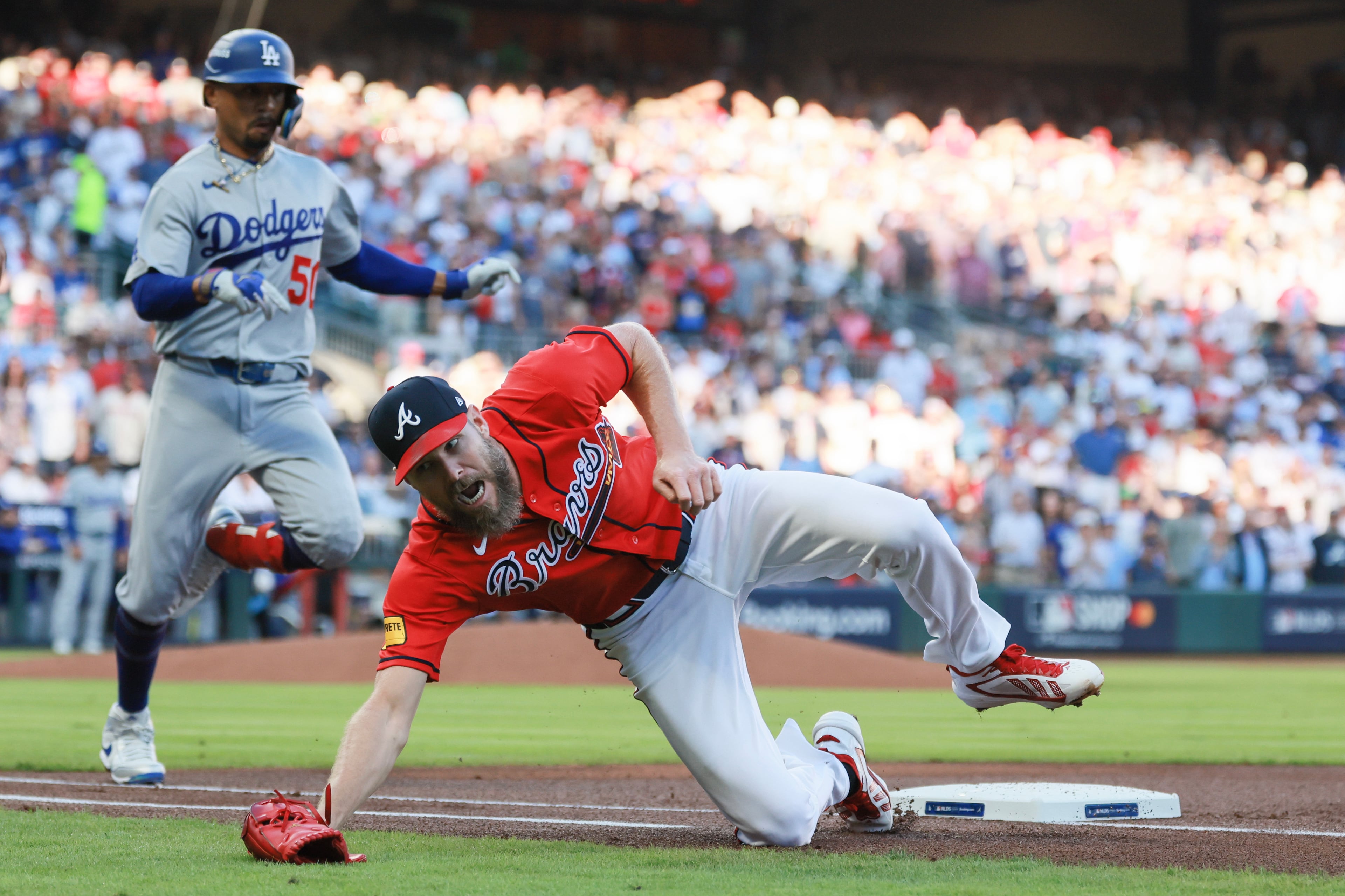 Atlanta Braves pitcher Chris Sale, right, is drawn off the bag on an awkward throw from first baseman Matt Olson on an infield hit by Los Angeles Dodgers shortstop Mookie Betts (50) during the first inning of Game 3 of the MLB National League Division Series between the Atlanta Braves and the Los Angeles Dodgers, Tuesday, Oct. 6, 2026, in Atlanta. (Jason Getz/AJC)
