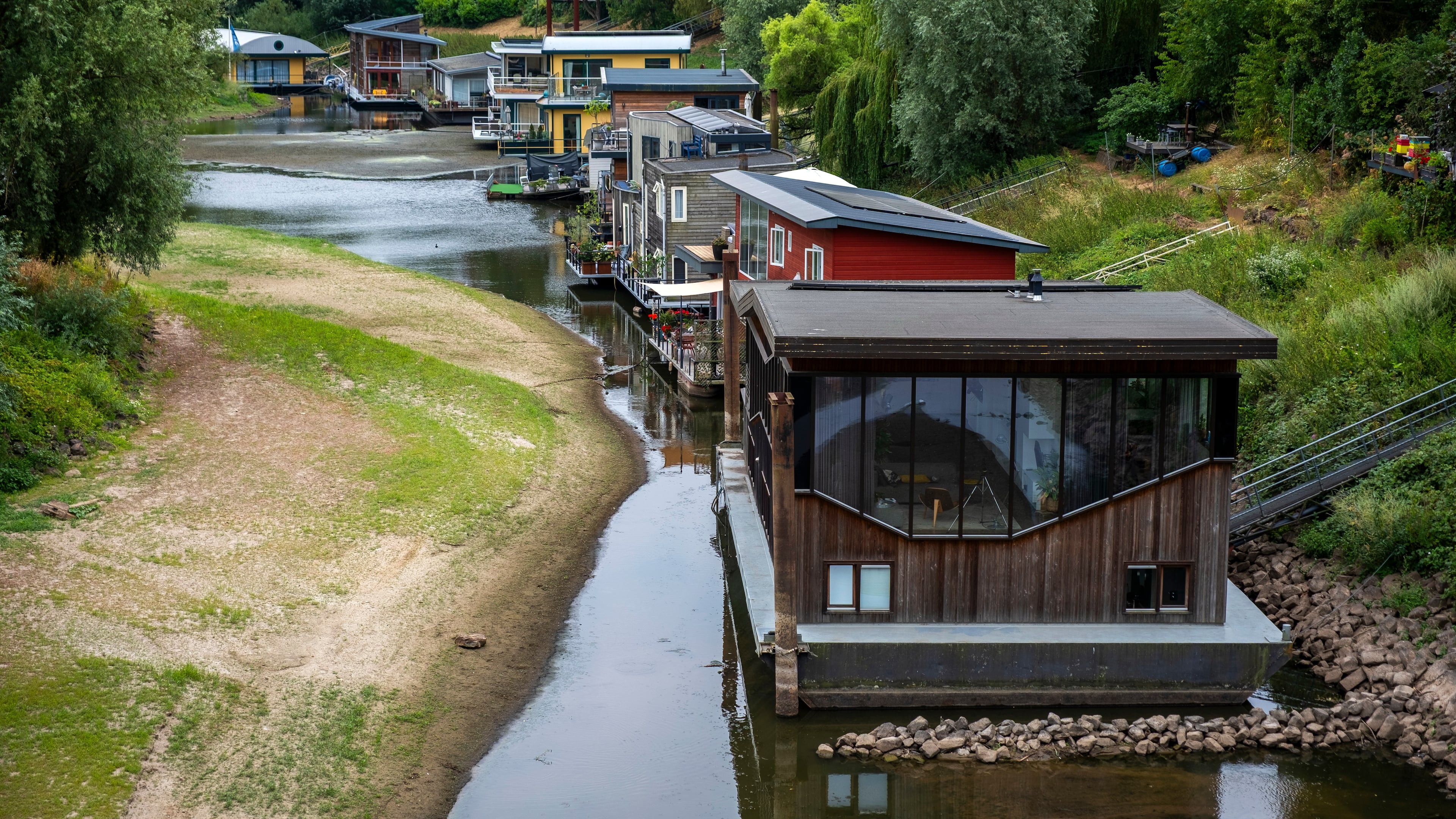 Houseboats sit in low water on the Waal river in Nijmegen, Netherlands, Thursday, July 30, 2026, due to drought conditions. (AP Photo/Patrick Post)