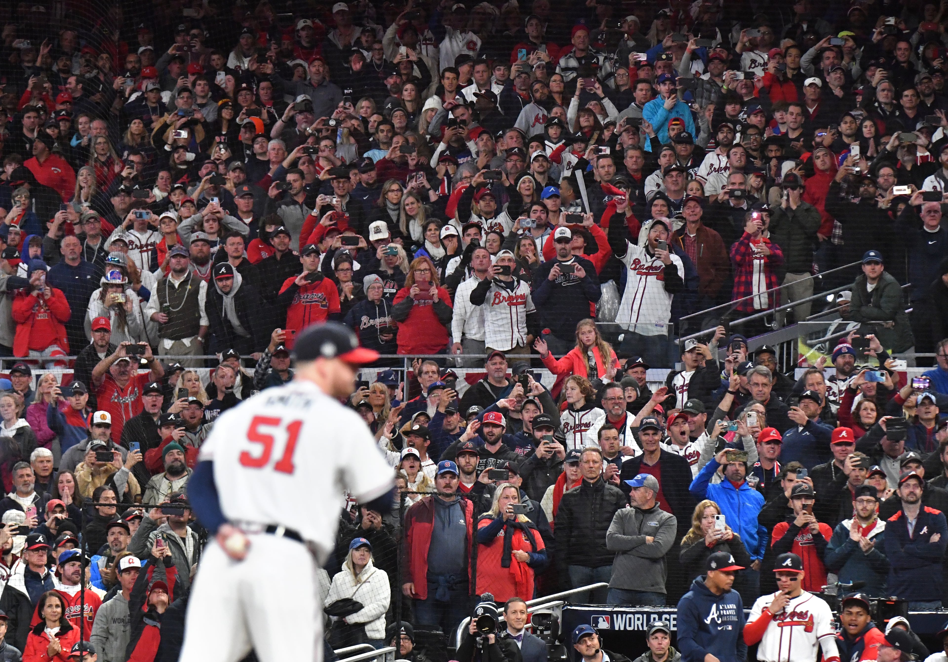 October 30, 2021 Atlanta - Baseball fans hold their smartphones Atlanta Braves relief pitcher Will Smith (51) throws a pitch to win over Houston Astros during Game 4 of baseball's World Series between Atlanta Braves and Houston Astros at Truist Park in Atlanta on Saturday, October 30, 2021. (Hyosub Shin / Hyosub.Shin@ajc.com)
