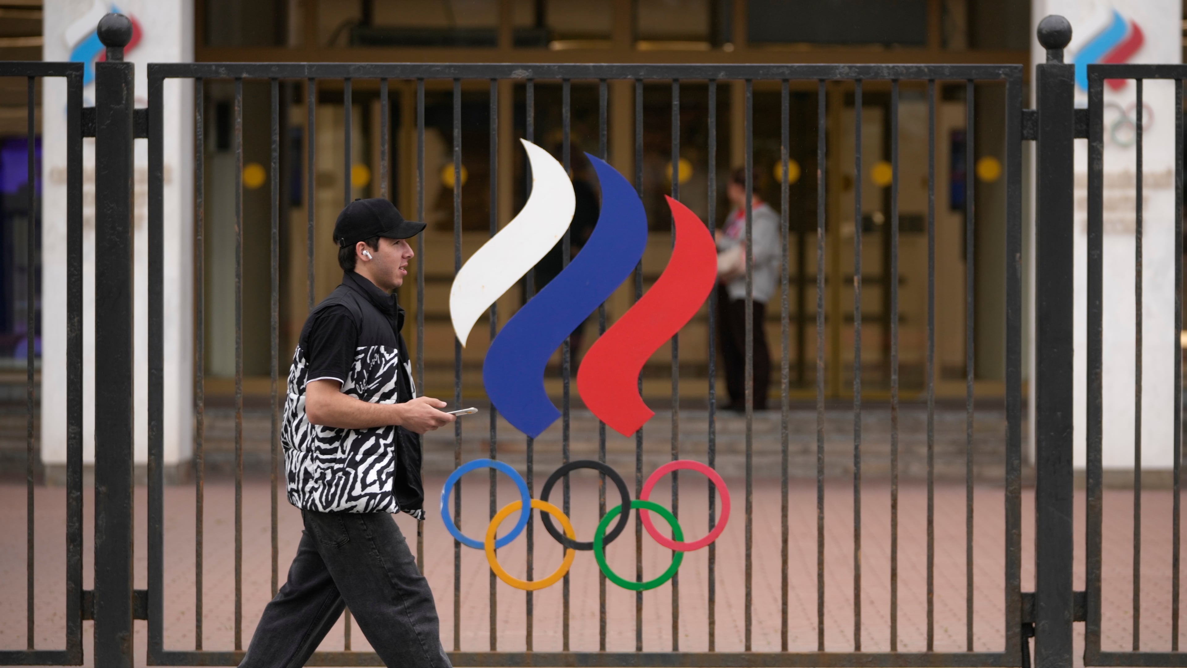 A man walks past a fence with Olympic Rings in front of the Russian National Olympic Committee building in Moscow, on Tuesday, July 7, 2026. (AP Photo/Pavel Bednyakov)