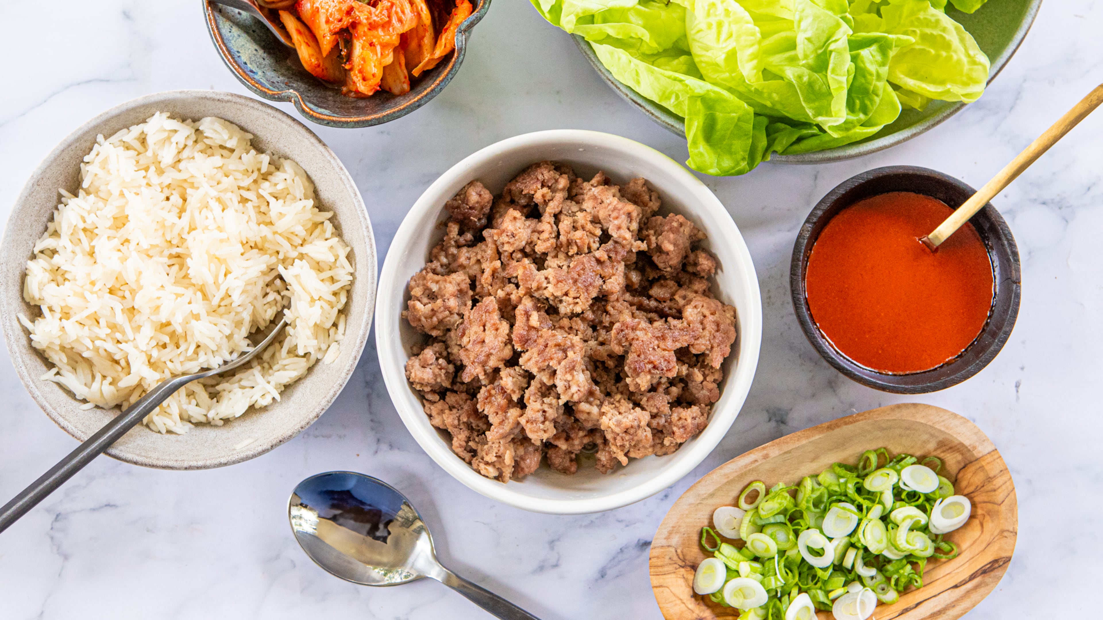 Bo ssam (the Korean word for "wrapped"), is a Korean take on lettuce wraps filled with ground pork. Serve the wraps family style, topped with kimchi, scallions and gochujang sauce, with rice on the side. (Aaliyah Man for the AJC/Food styling by Kate Williams)