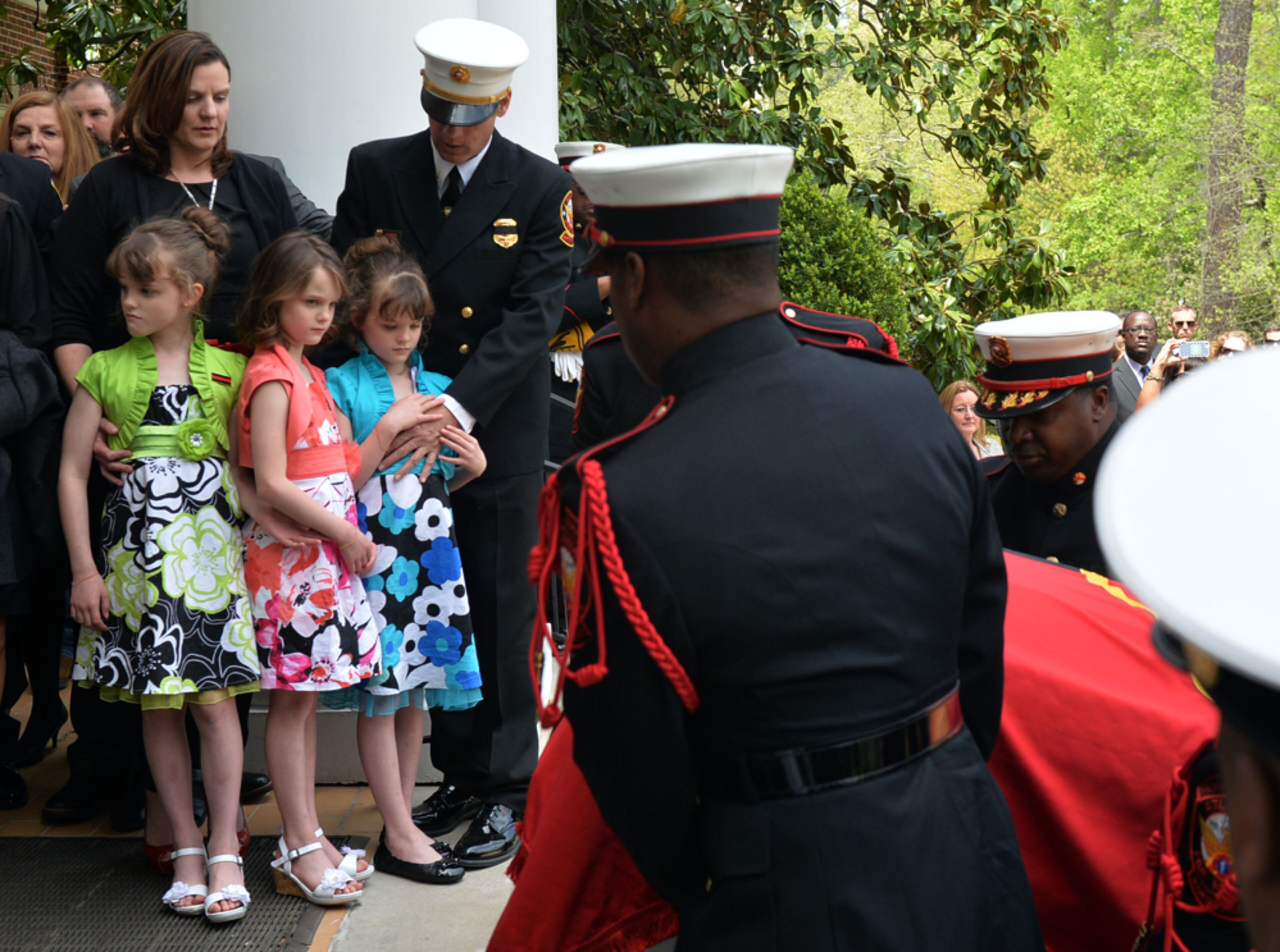 KEEPING EACH OTHER STRONG--APRIL 17, 2014 ATLANTA Sgt Guinn's widow, Kimberly, stands with their 7 year old triplets, Isabelle, Alyssa, and Makenna as the casket enters the church. Atlanta Fire Rescue officials and firefighters joined with family and friends during the funeral of AFR Sgt Frank Guinn at Peachtree Road Presbyterian Church, Thursday, April 17, 2014. Sgt Guinn, 36, was training for an Ironman Triathlon in New Orleans when he was struck on his bicycle and killed. Guinn, a nine-year veteran of the department, was stationed at Fire Station 21. He is survived by his wife, a Cobb County teacher, and 7-year-old triplet daughters. KENT D. JOHNSON/KDJOHNSON@AJC.COM