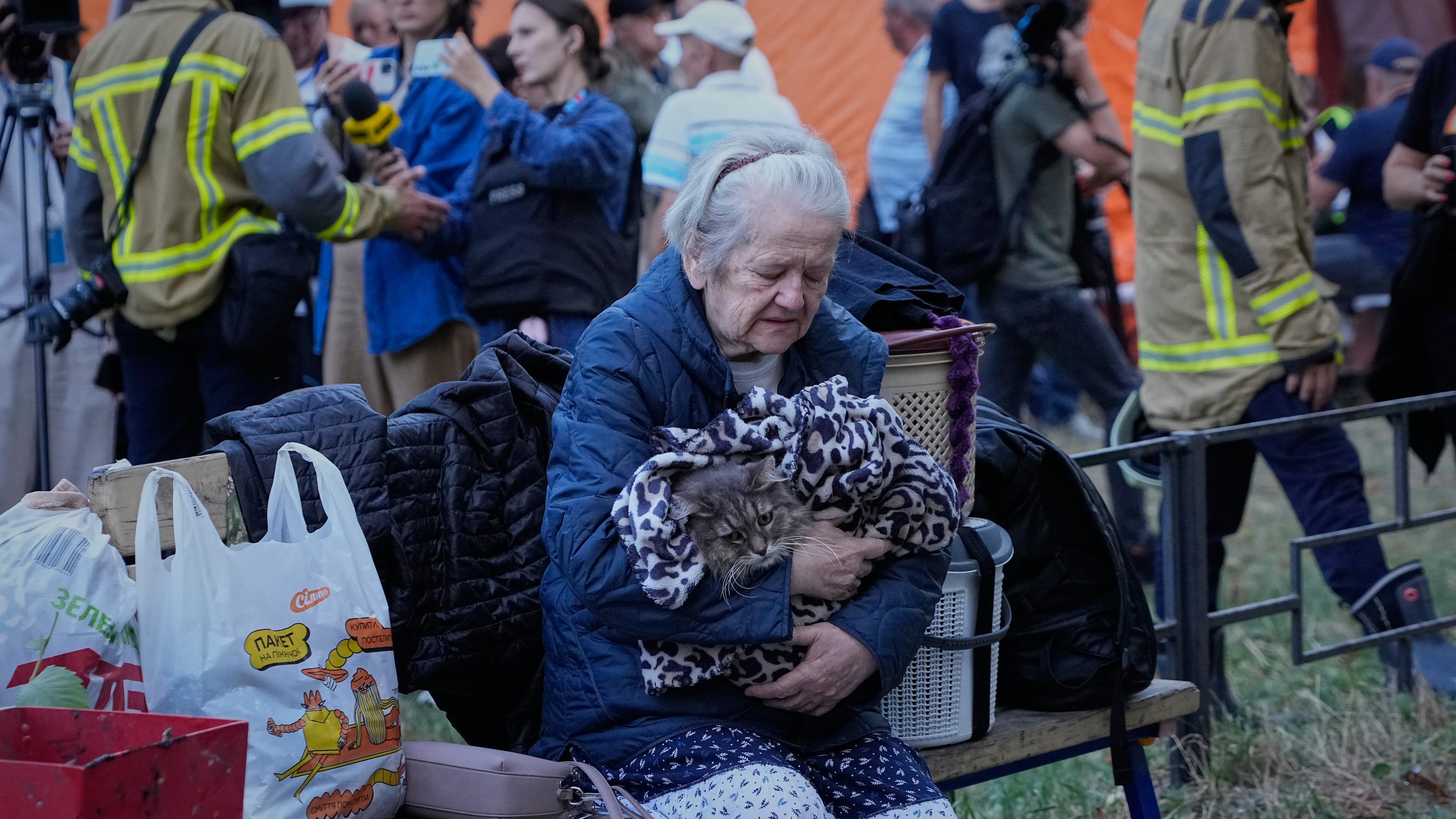 An elderly woman holds her car as she sits with her belongings in front of heavily damaged residential buildings after an overnight Russian attack, in Kyiv, Ukraine, Thursday, Aug. 20, 2026. (AP Photo/Efrem Lukatsky)