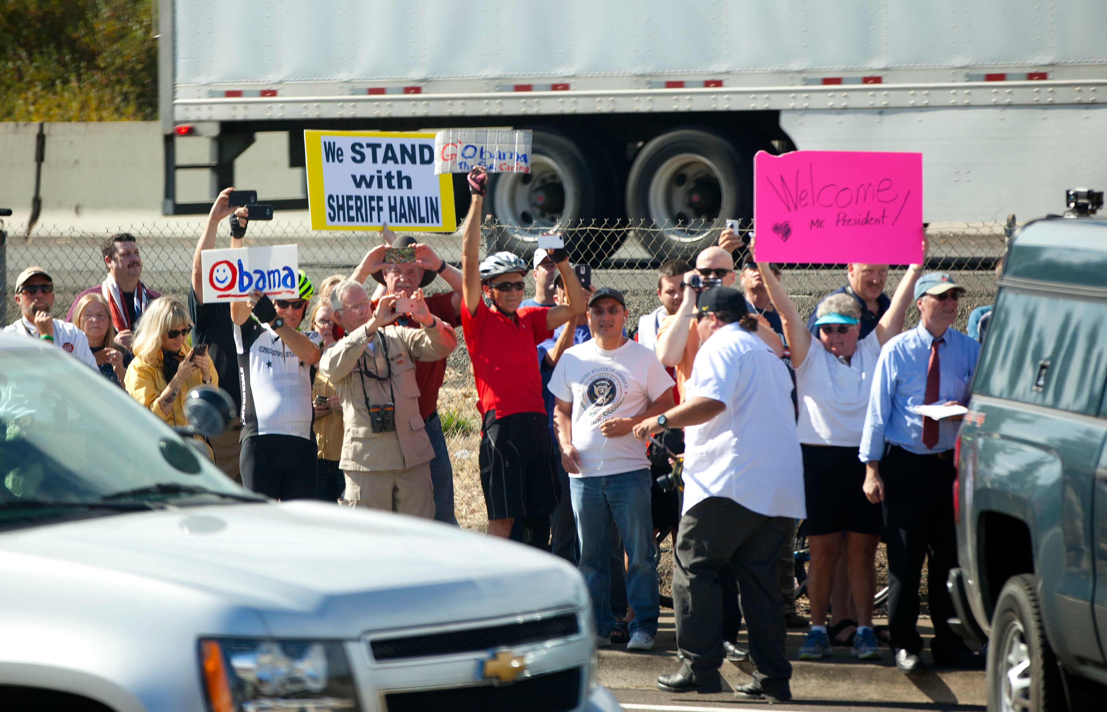 People gather outside Roseburg Municipal Airport to watch motorcade transporting President Barack Obama head towards Roseburg H.S., Friday, Oct. 9, 2015 in Roseburg, Ore. Obama traveled to Roseburg, to meet with families of the victims of the Oct. 1, shooting at Umpqua Community College, as part of a four-day West Coast tour. Obama is also scheduled to attend a fundraiser event later today in Seattle with Sen. Patty Murray, D-Wash. He's is also attending fundraisers in San Francisco and Los Angeles during the four-day visit. (AP Photo/Pablo Martinez Monsivais)