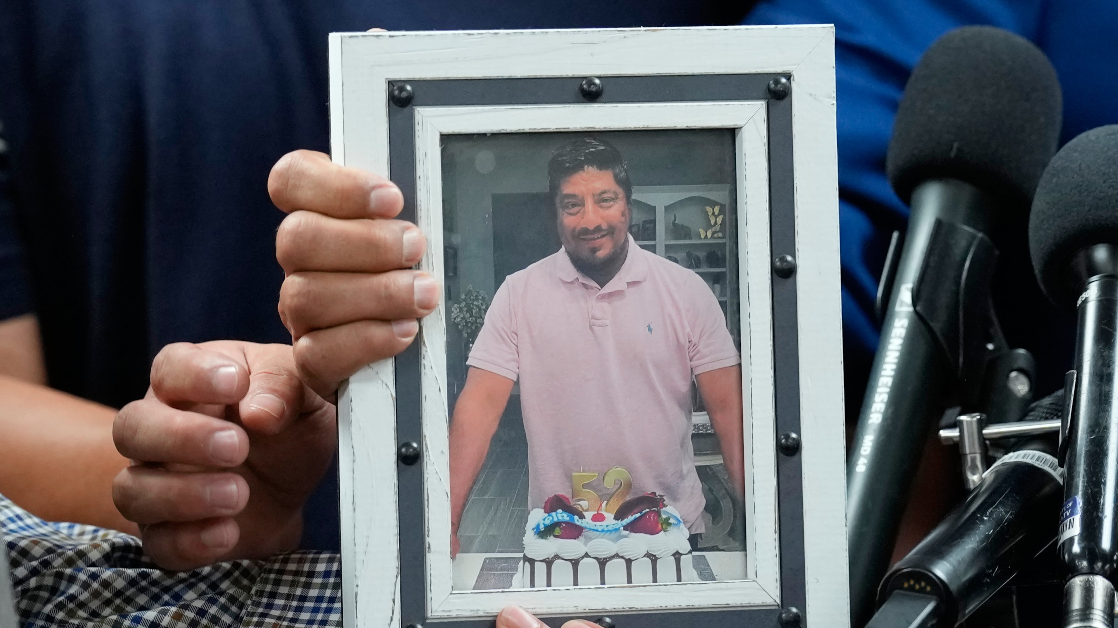 Ronaldo Salgado and Lorenzo Jr., sons of Lorenzo Salgado Araujo, hold a photograph of their father during a news conference Wednesday, July 8, 2026, in Houston. (AP Photo/David J. Phillip)