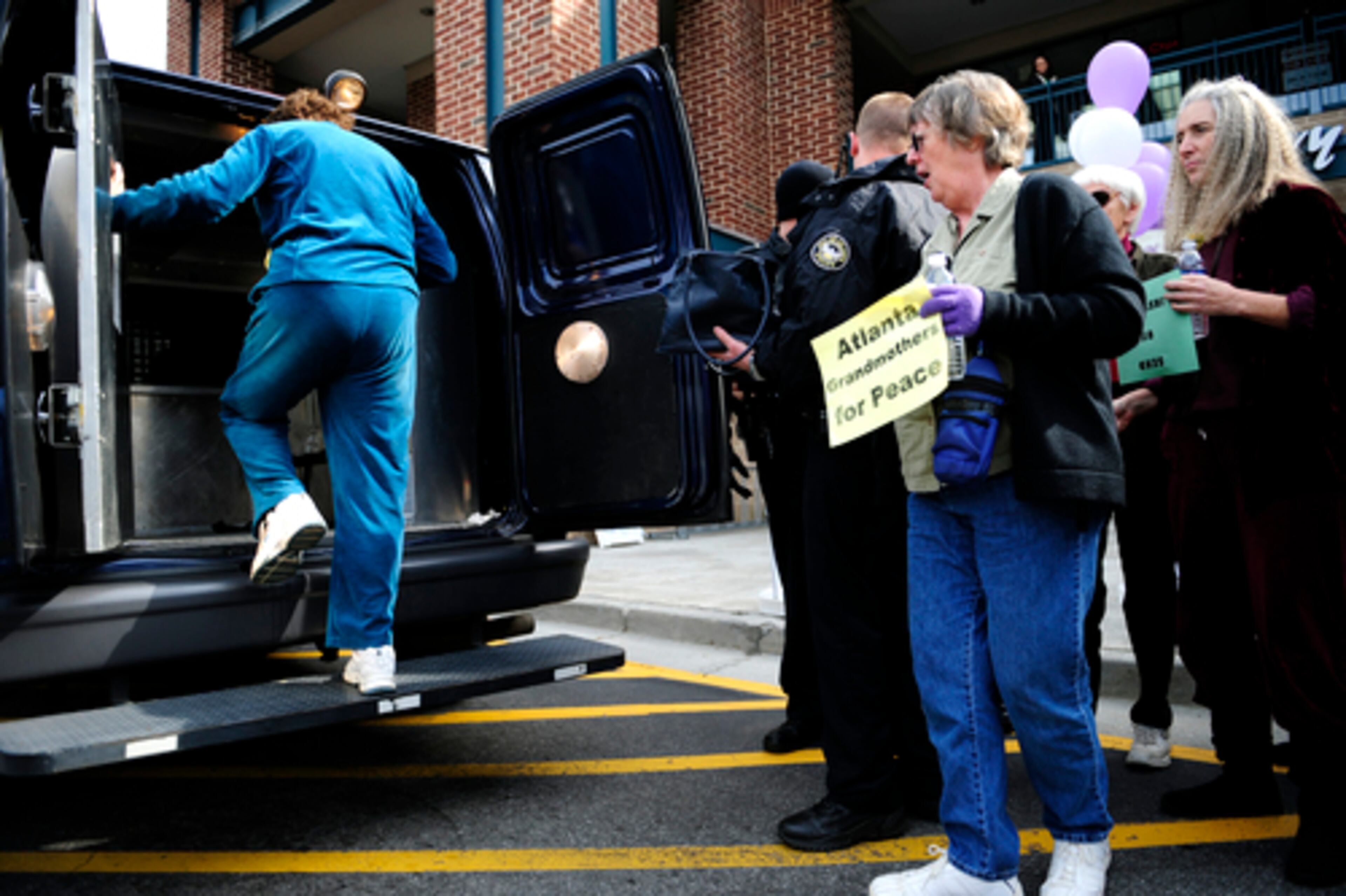 Hunnicutt steps into a police van after being arrested during the protest. Fellow Grandmothers for Peace Susan Keith (from left) and Judy Conder watch.