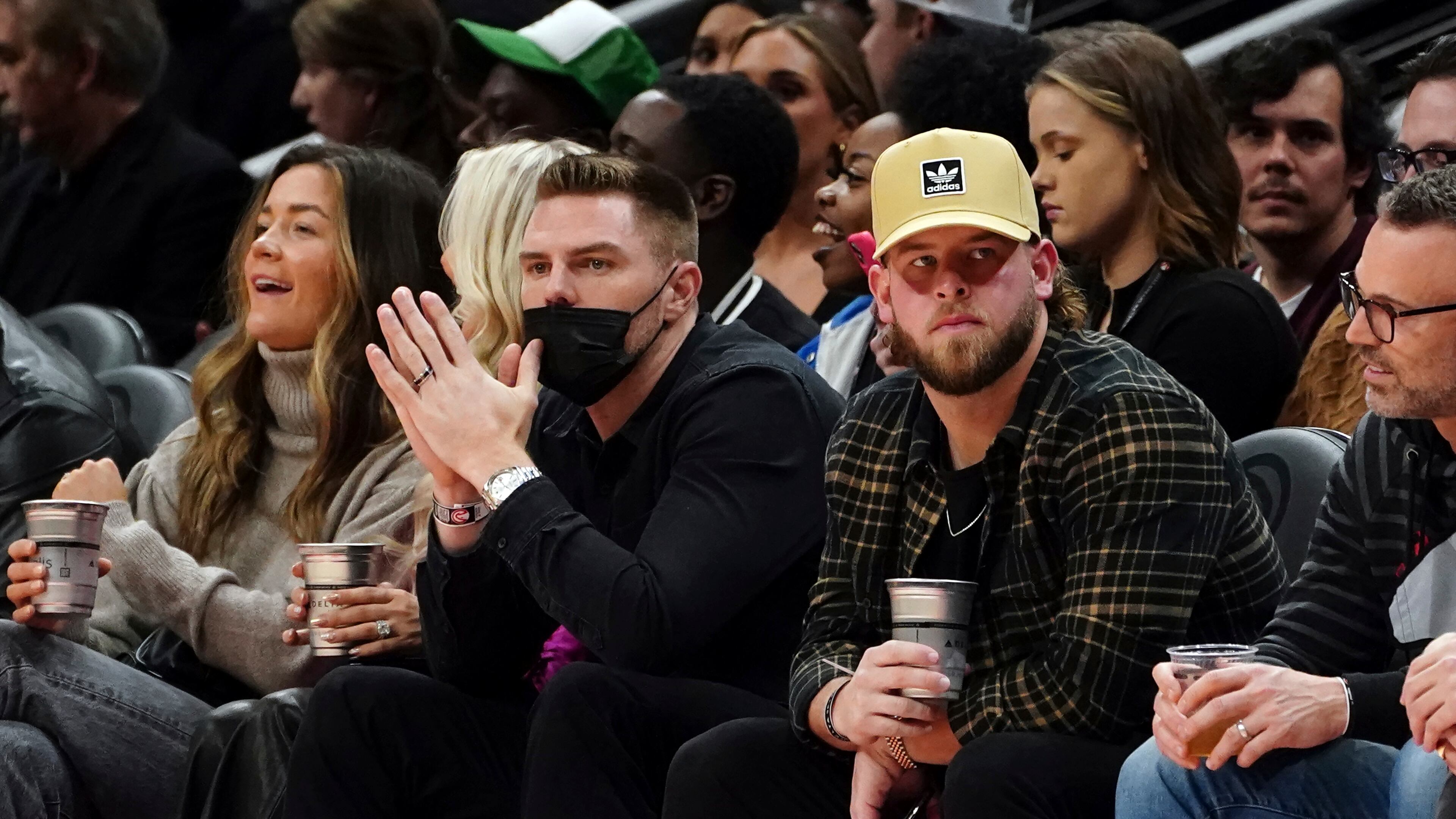 Atlanta Braves first baseman Freddie Freeman, center left, and relief pitcher A.J. Minter, center right, watch the first half of an NBA basketball game between the Atlanta Hawks and the Utah Jazz, Thursday, Nov. 4, 2021, in Atlanta. (AP Photo/John Bazemore)