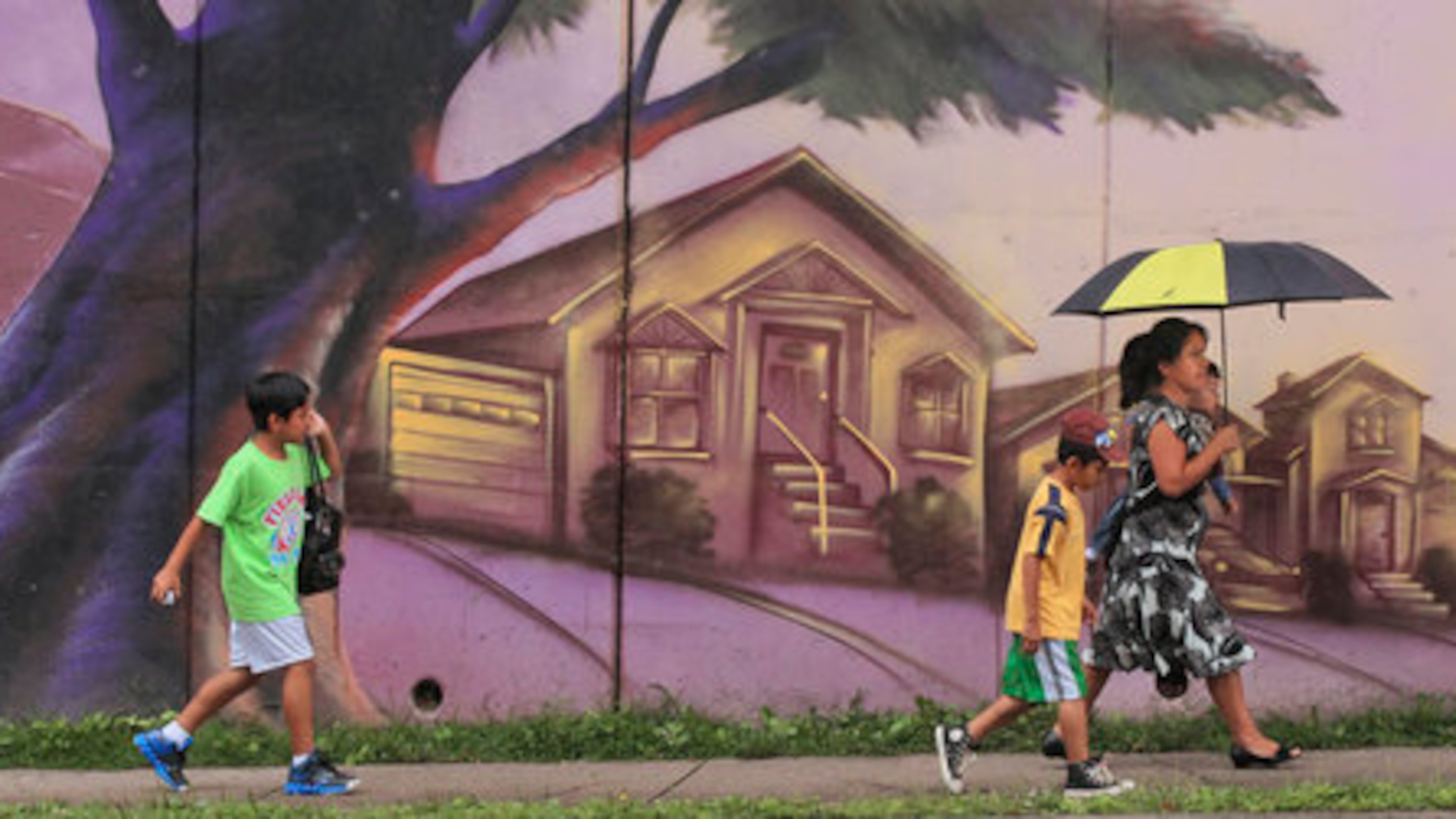 Magdalena Bartolon holding 1-year old son, Rodrigo (right) is followed by sons, Anderson-8 (center) and Edson-9 (left) as they walked along the mural on Chamblee Dunwoody Road near American Industrial Way in Chamblee on Monday June, 11, 2012. JOHN SPINK / JSPINK@AJC.COM