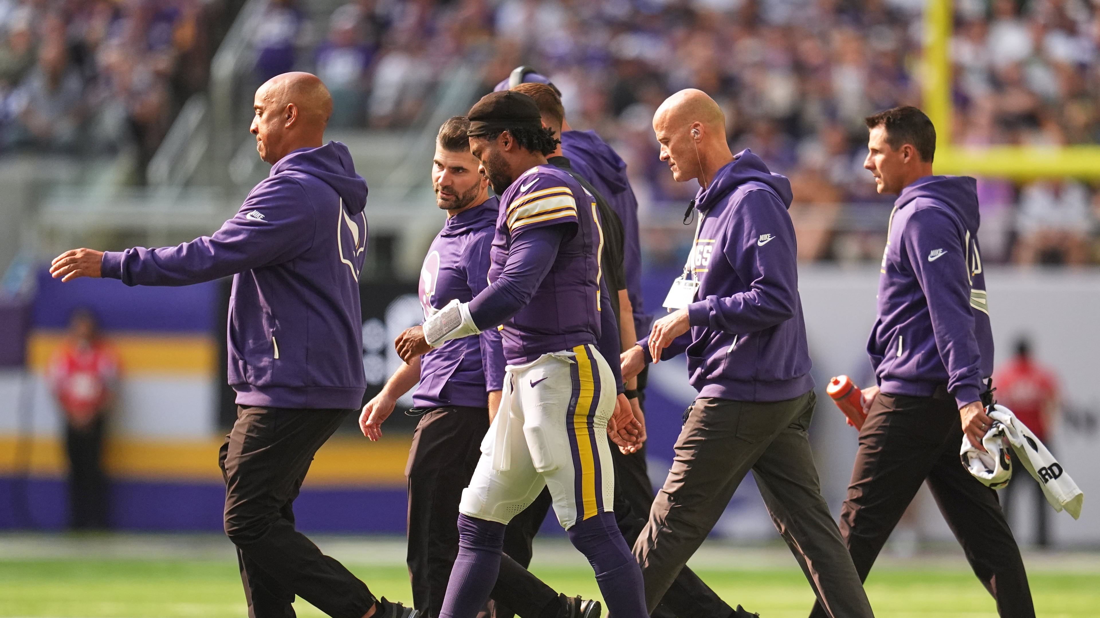 Minnesota Vikings quarterback Kyler Murray, center, walks off the field with staff after suffering an unknown injury during the first half of an NFL football game against the Green Bay Packers Sunday, Sept. 13, 2026, in Minneapolis, Minn. (AP Photo/Abbie Parr)