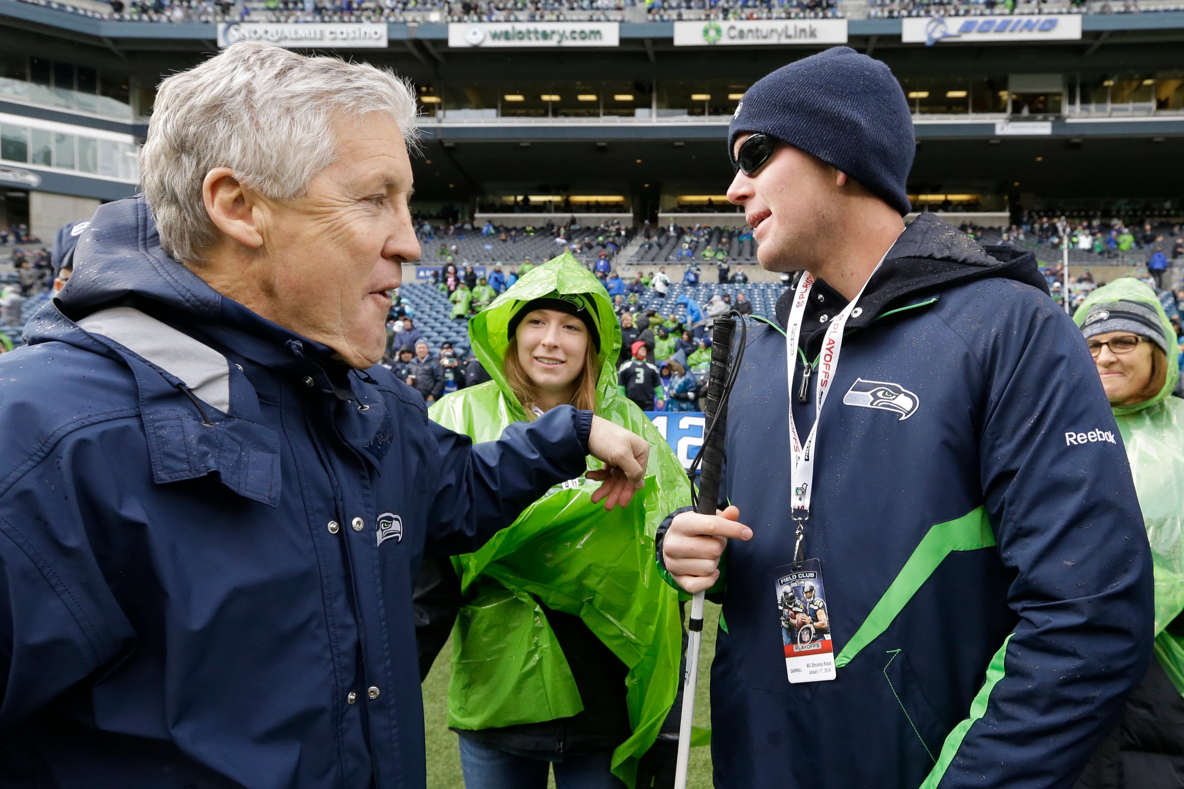 FILE - In this Jan. 11, 2014, file photo, Seattle Seahawks head coach Pete Carroll, left, talks with Jake Olson, 16, before an NFC divisional playoff NFL football game against the New Orleans Saints in Seattle. Olson, a blind football player who is a long-snapper attending Southern California on a special athletic scholarship for physically challenged athletes, practiced with for the first time with the sixth-ranked Trojans, Tuesday, Sept. 15, 2015. Eligibility issues had prevented him from officially joining the team until Tuesday. (AP Photo/Elaine Thompson, File)