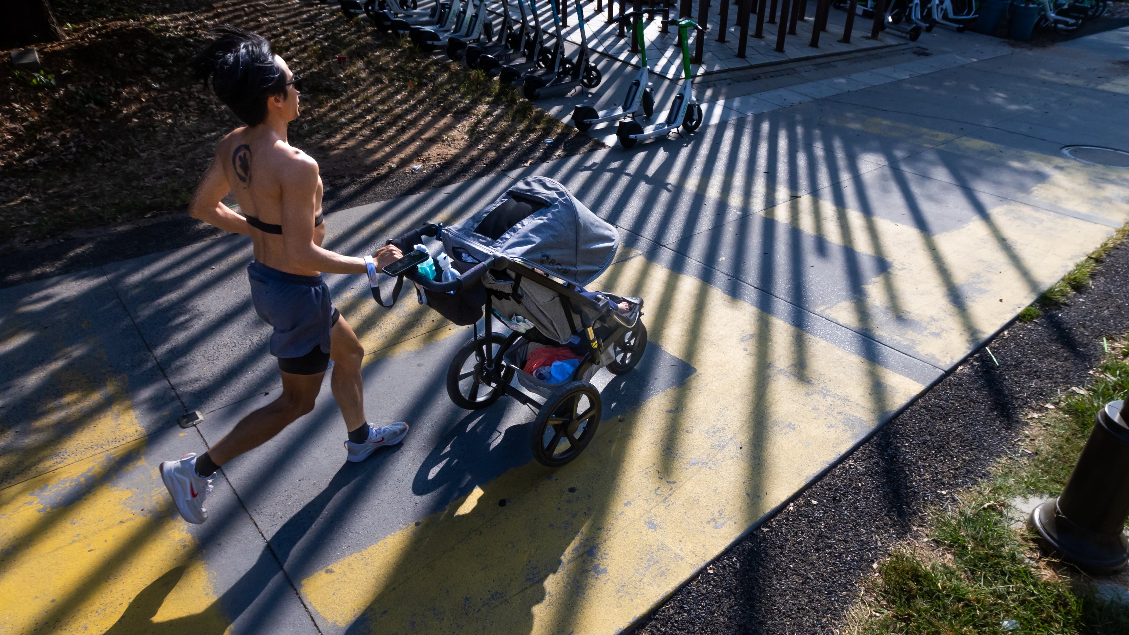 Dow Lin pushes his 14-month old son in the shadows of the Steel Columns Sculpture on the Beltline Eastside Trail at Angier Springs Road on a mild Tuesday, Sept. 10, 2024. (John Spink/AJC)