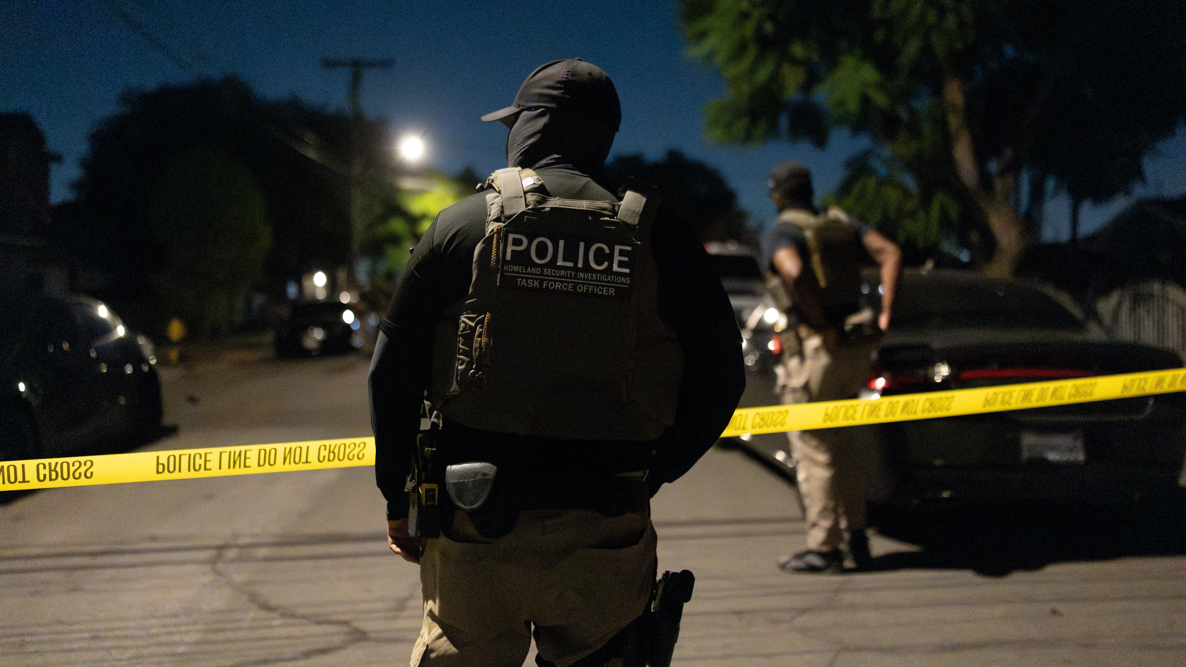 A Homeland Security Investigations task force officer stands near police tape marking a perimeter during a federal operation targeting suspected illegal voter registration in Commerce, Calif., Monday, Oct. 19, 2026. (AP Photo/Jae C. Hong)