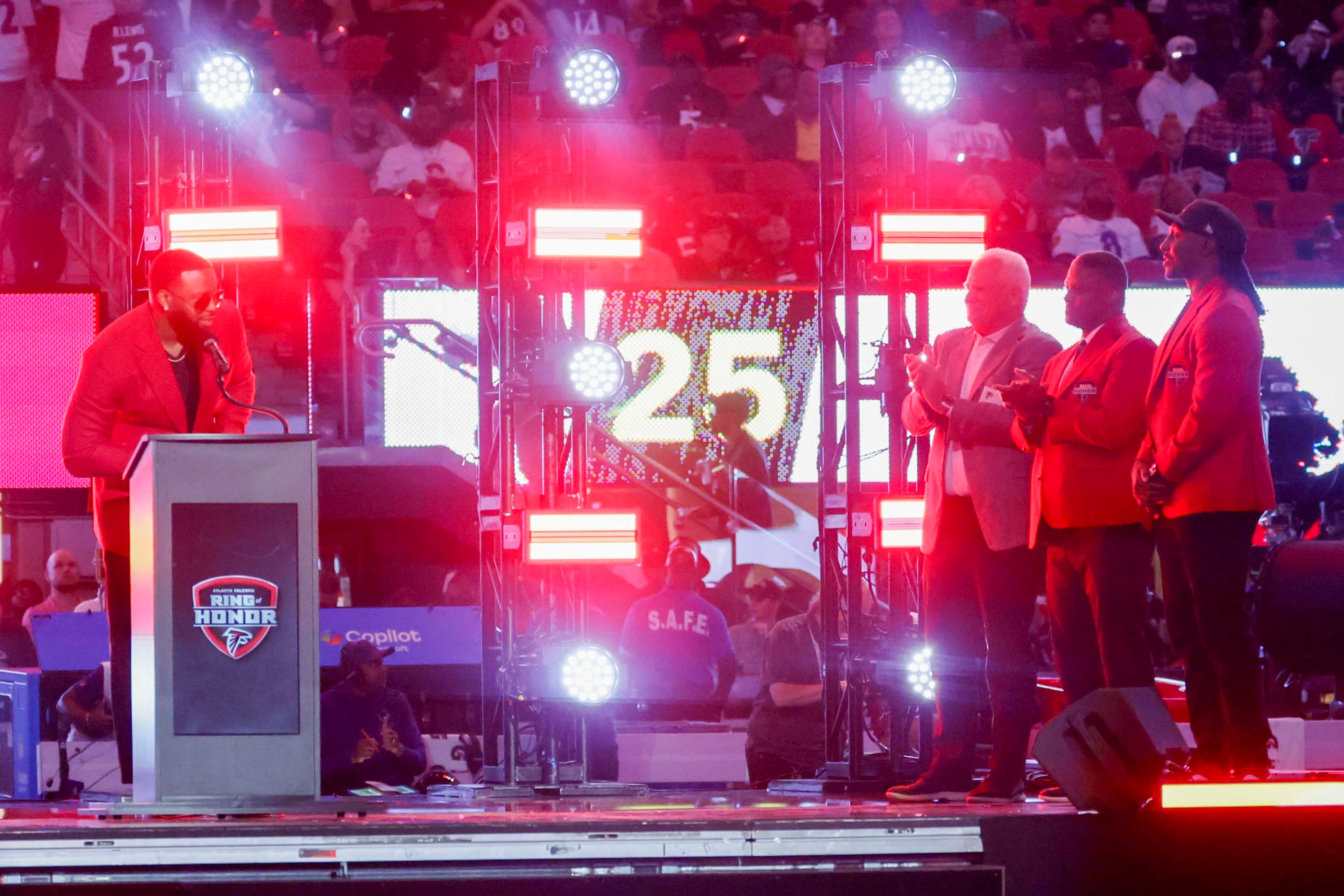 Former Atlanta Falcons defensive end John Abraham (left) addresses the crowd during his Ring of Honor induction ceremony at halftime of an NFL game between the Baltimore Ravens and the Atlanta Falcons at Mercedes-Benz Stadium in Atlanta, GA, Sunday, Oct. 11, 2026. (Miguel Martinez/AJC)