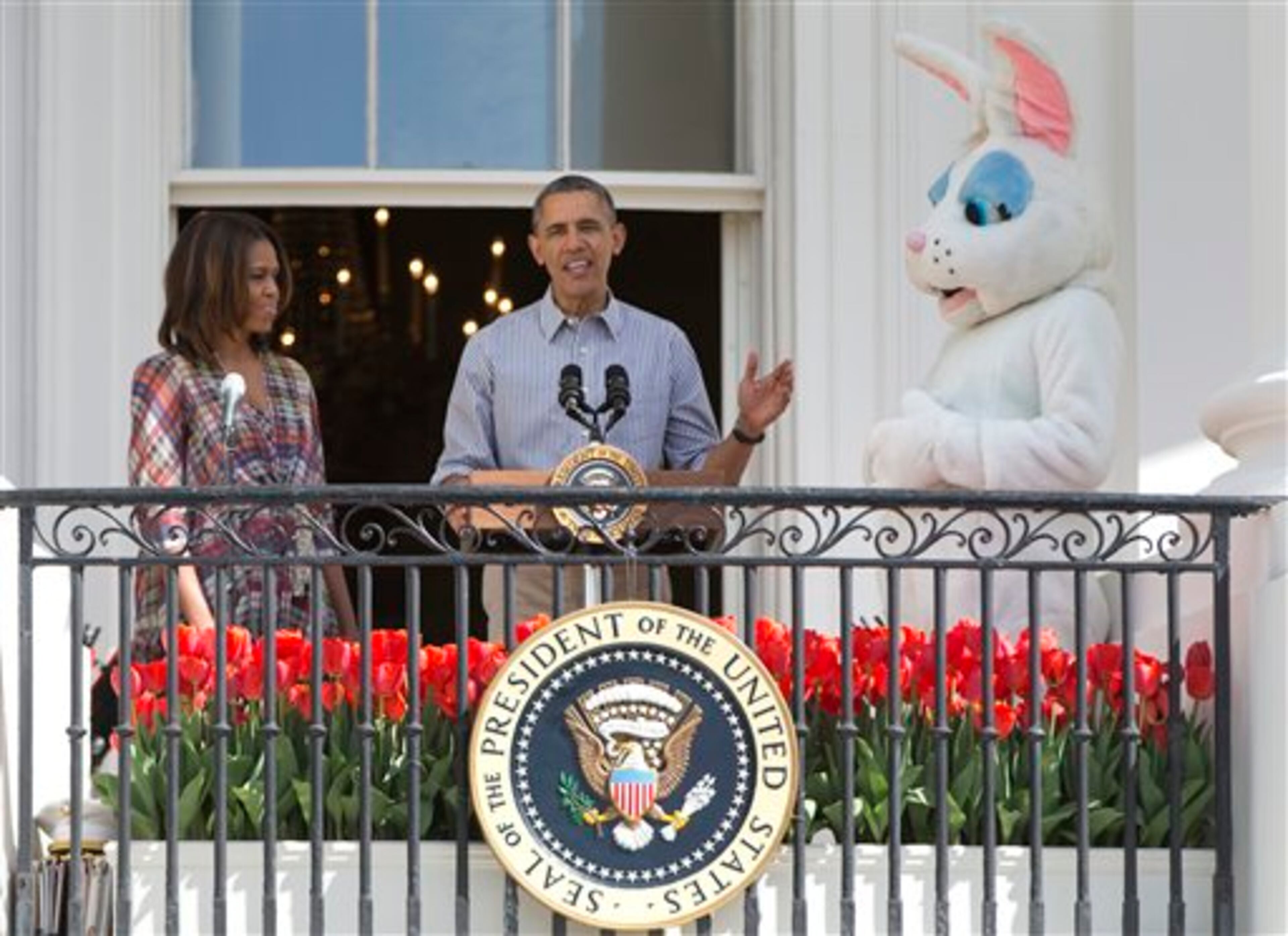 President Barack Obama, flanked by lady Michelle Obama, and the Easter Bunny, gestures as he speak as they stand on the Truman Balcony of the White House in Washington, Monday, April 21, 2014, during the White House Easter Egg Roll on the South Lawn. Thousands of children are gathered at the White House for the annual Easter Egg Roll. This year's event features live music, cooking stations, storytelling, and of course, some Easter egg rolling. (AP Photo/Carolyn Kaster)
