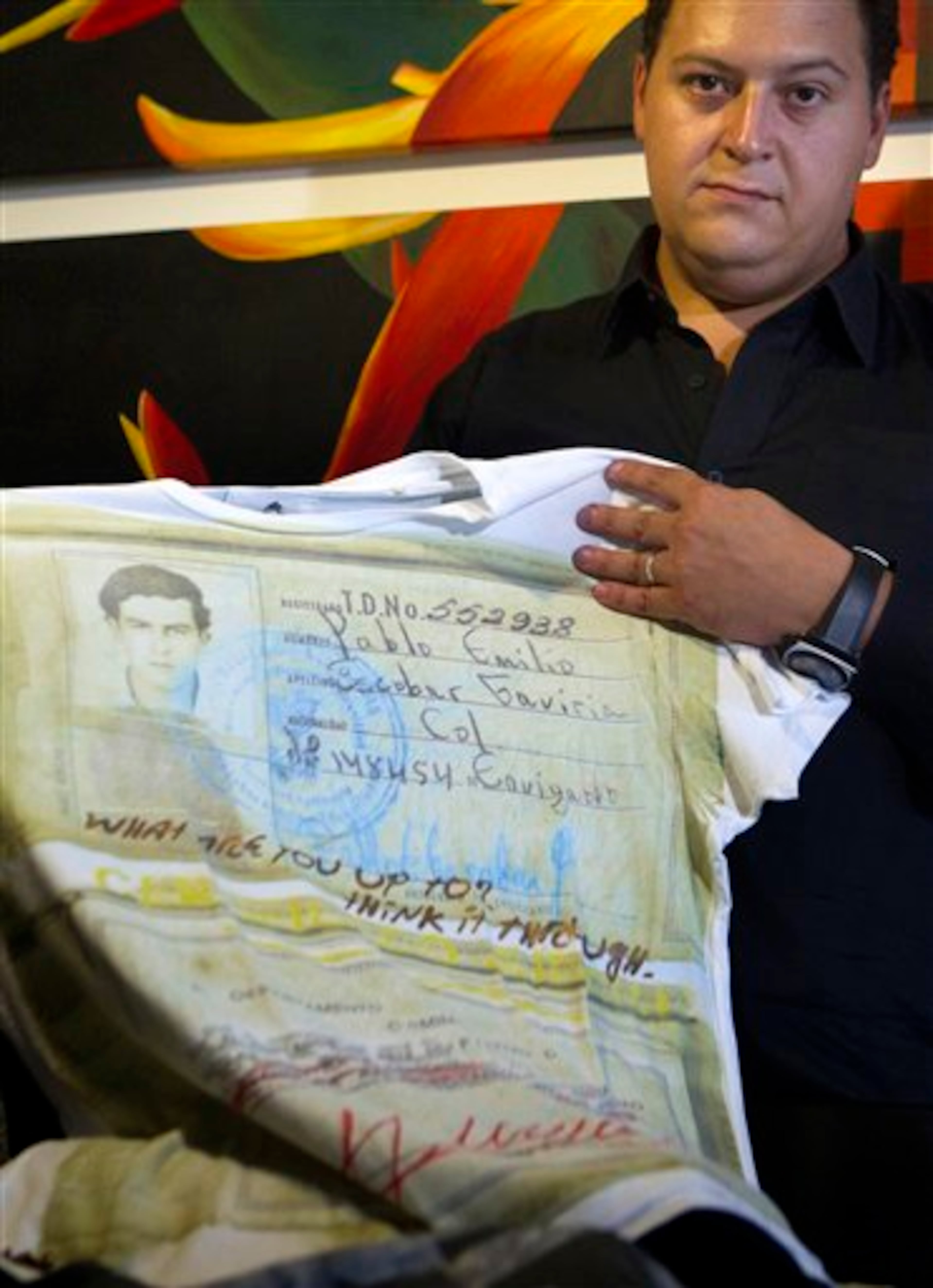 Sebastian Marroquin, son of Colombia's late drug lord Pablo Escobar, shows a shirt from his new clothing line "Escobar Henao," covered with an image of his father's identity card and reads "What are you up to? Think it through," at his home in Buenos Aires, Argentina, Friday, Aug. 17, 2012. Escobar was a Colombian drug lord who died at age 44 while fleeing from police. In his lifetime, he had a Robin-Hood image among some poor areas of Medellin, Colombia. (AP Photo/Eduardo Di Baia)