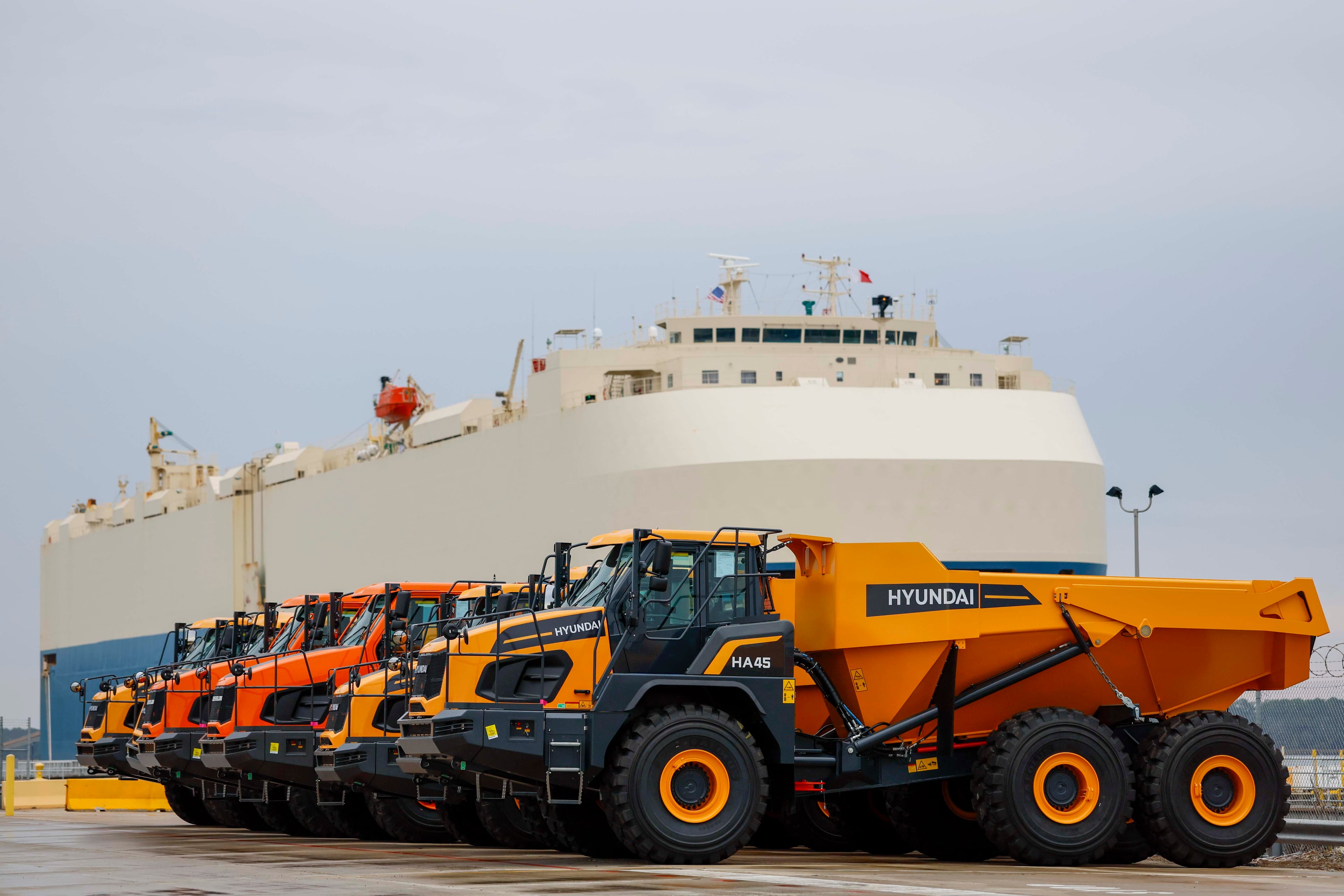 Dump trucks are parked as a ship prepares to depart the Georgia Port Authority in Brunswick, Ga., on Wednesday, Jan. 14, 2026. The GPA has invested in import-export facilities at its Brunswick terminal for heavy equipment manufacturers, including roll-in and roll-out, and a roofed facility for final assembly. (Miguel Martinez/AJC)