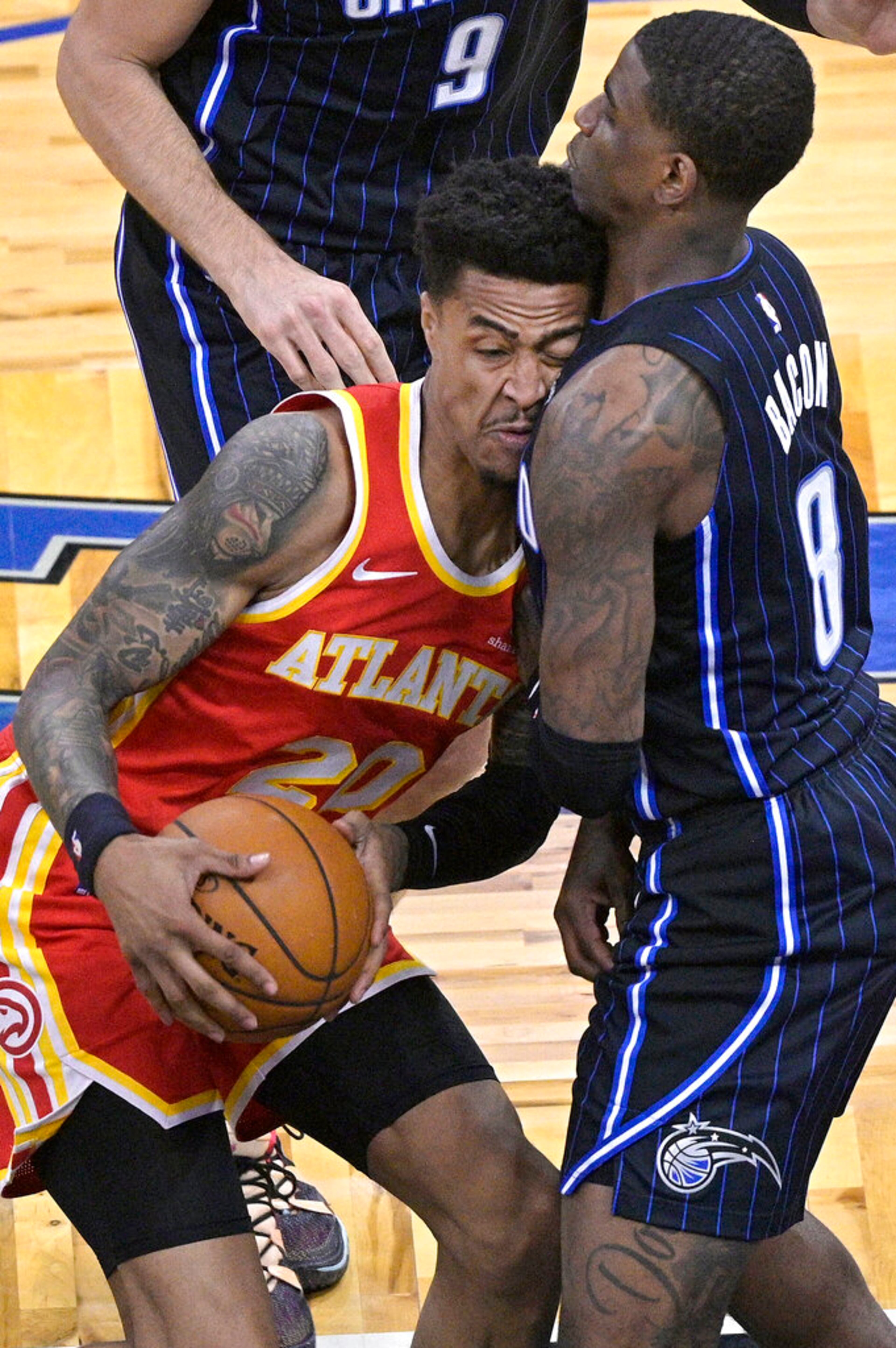 Atlanta Hawks forward John Collins (20) collides with Orlando Magic forward Dwayne Bacon (8) while driving to the basket during the first half of an NBA basketball game Wednesday, March 3, 2021, in Orlando, Fla. (AP Photo/Phelan M. Ebenhack)