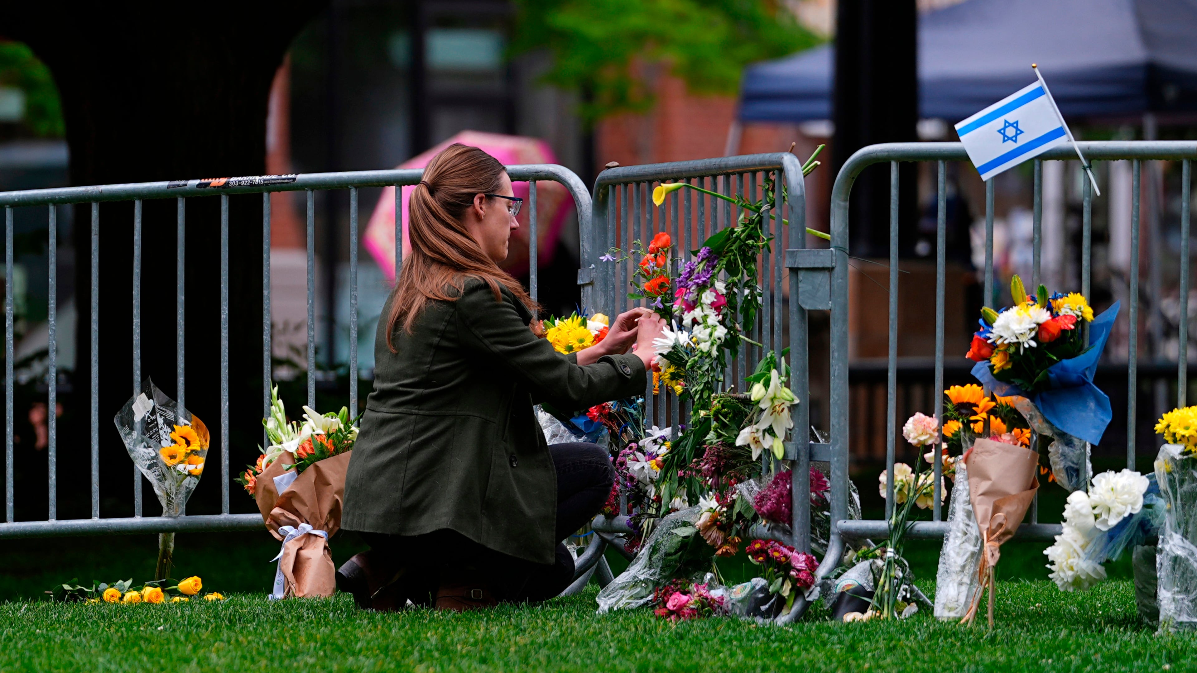 FILE - A woman places a bouquet of flowers at a makeshift memorial for victims of an attack outside of the Boulder County, Colo., courthouse Tuesday, June 3, 2025, in Boulder, Colo. (AP Photo/David Zalubowski, File)