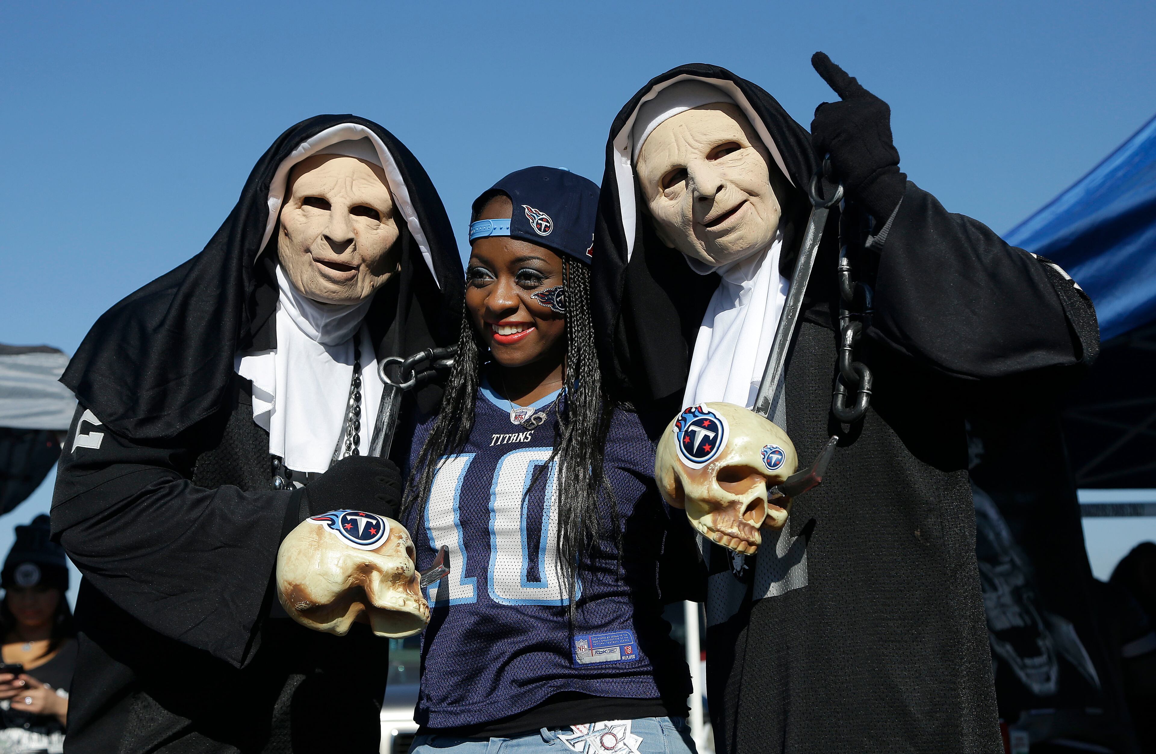 Oakland Raiders fans Chris and Sue�astenda, left and right, pose for photos with Tennessee Titans fan Morgan Davis in the O.co Coliseum parking lot before an NFL football game in Oakland, Calif., Sunday, Nov. 24, 2013. (AP Photo/Jeff Chiu)